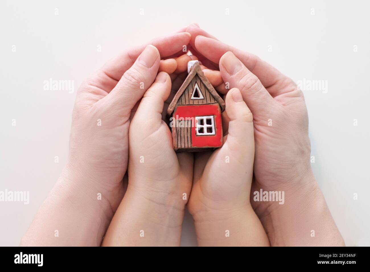 immobiliare e casa di famiglia concetto - closeup immagine di bambino e le mani femminili tenendo rosso casa di carta con la famiglia. Foto di alta qualità Foto Stock