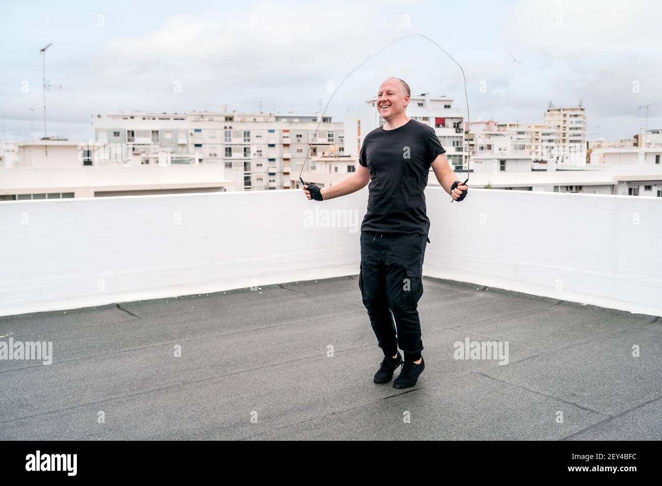 Un uomo che si esercita sul tetto utilizzando una corda che salta durante il blocco, Portogallo Foto Stock