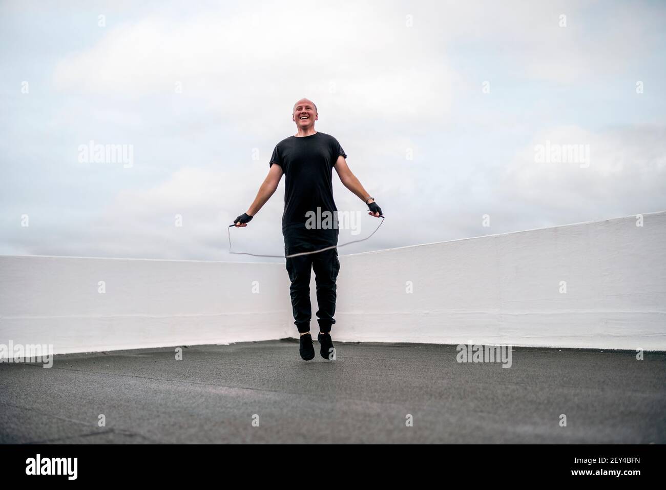 Un uomo che si esercita sul tetto utilizzando una corda che salta durante il blocco, Portogallo Foto Stock
