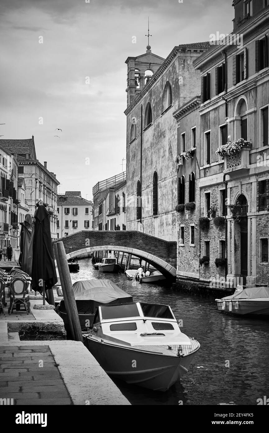 Canale veneziano con ponte e motoscafi ormeggiati, Venezia, Italia. Fotografia in bianco e nero, paesaggio urbano Foto Stock