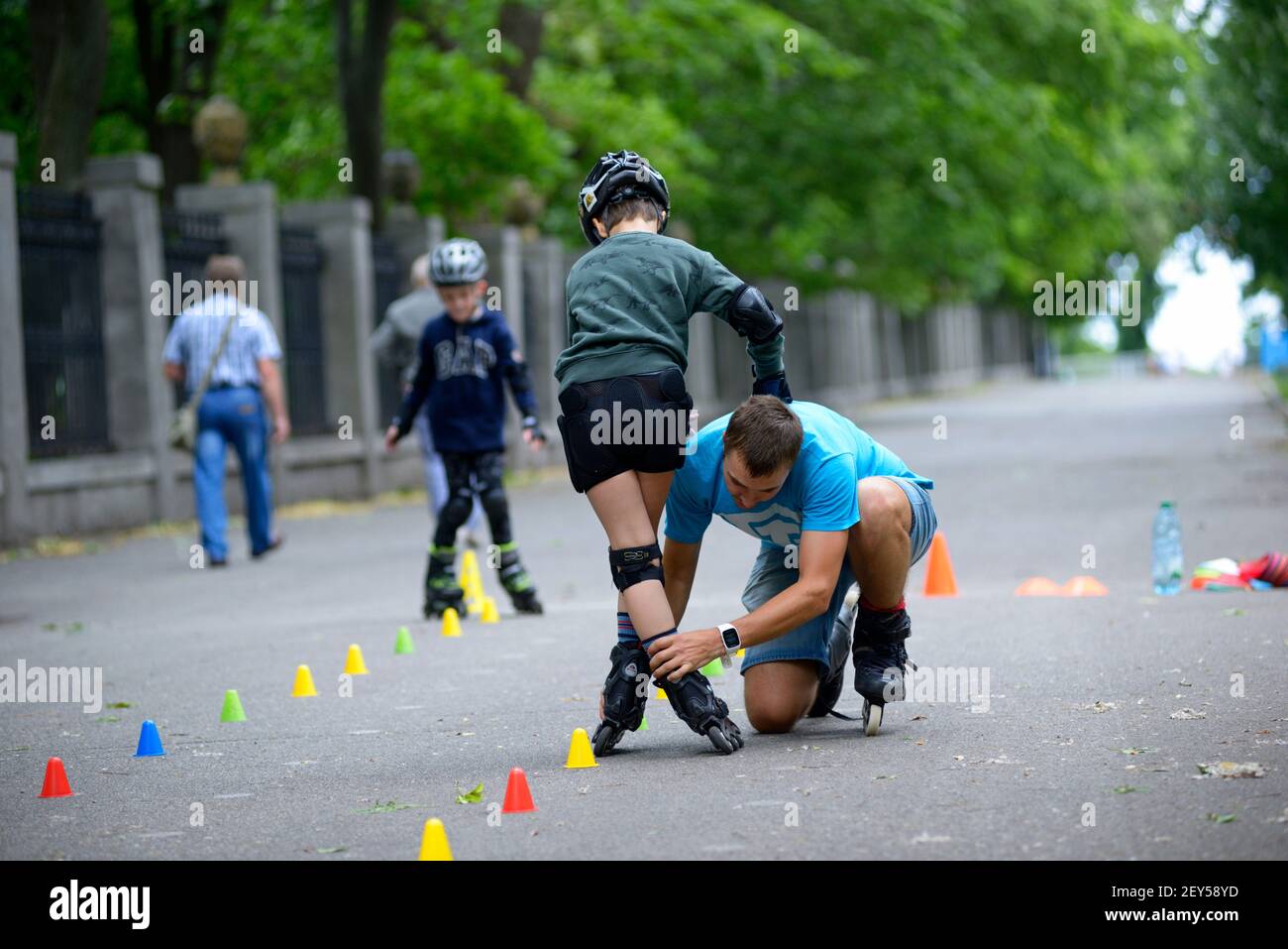 Rollerblading. Trainer corregge i movimenti delle gambe del ragazzo insegnando slalom artistico. 25 giugno 2019. Kiev, Ucraina Foto Stock