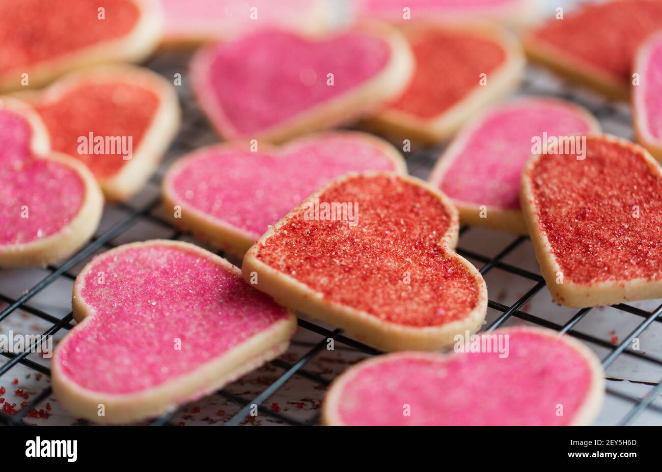 Primo piano di molti biscotti decorati a forma di cuore sulla griglia di raffreddamento. Foto Stock