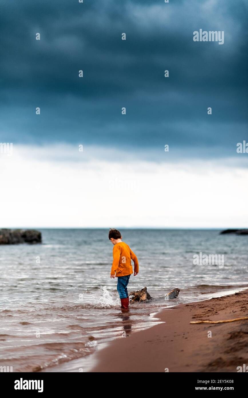 un ragazzino gli spruzzò il piede sul litorale di lago superiore Foto Stock