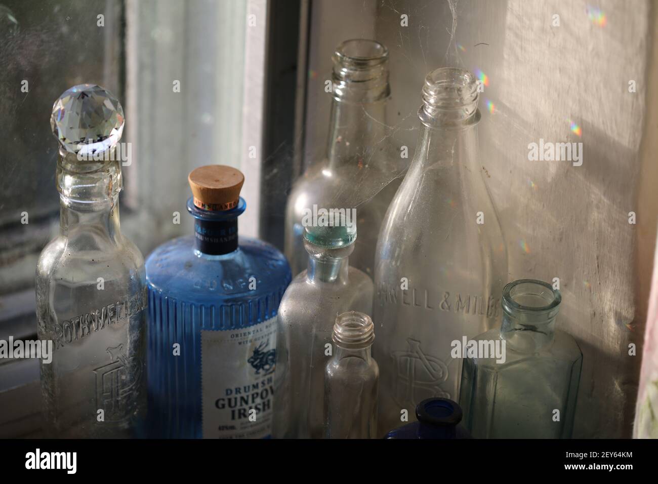 polverosi, ciottoli e bottiglie di vecchia classe con luce solare e arcobaleni Foto Stock