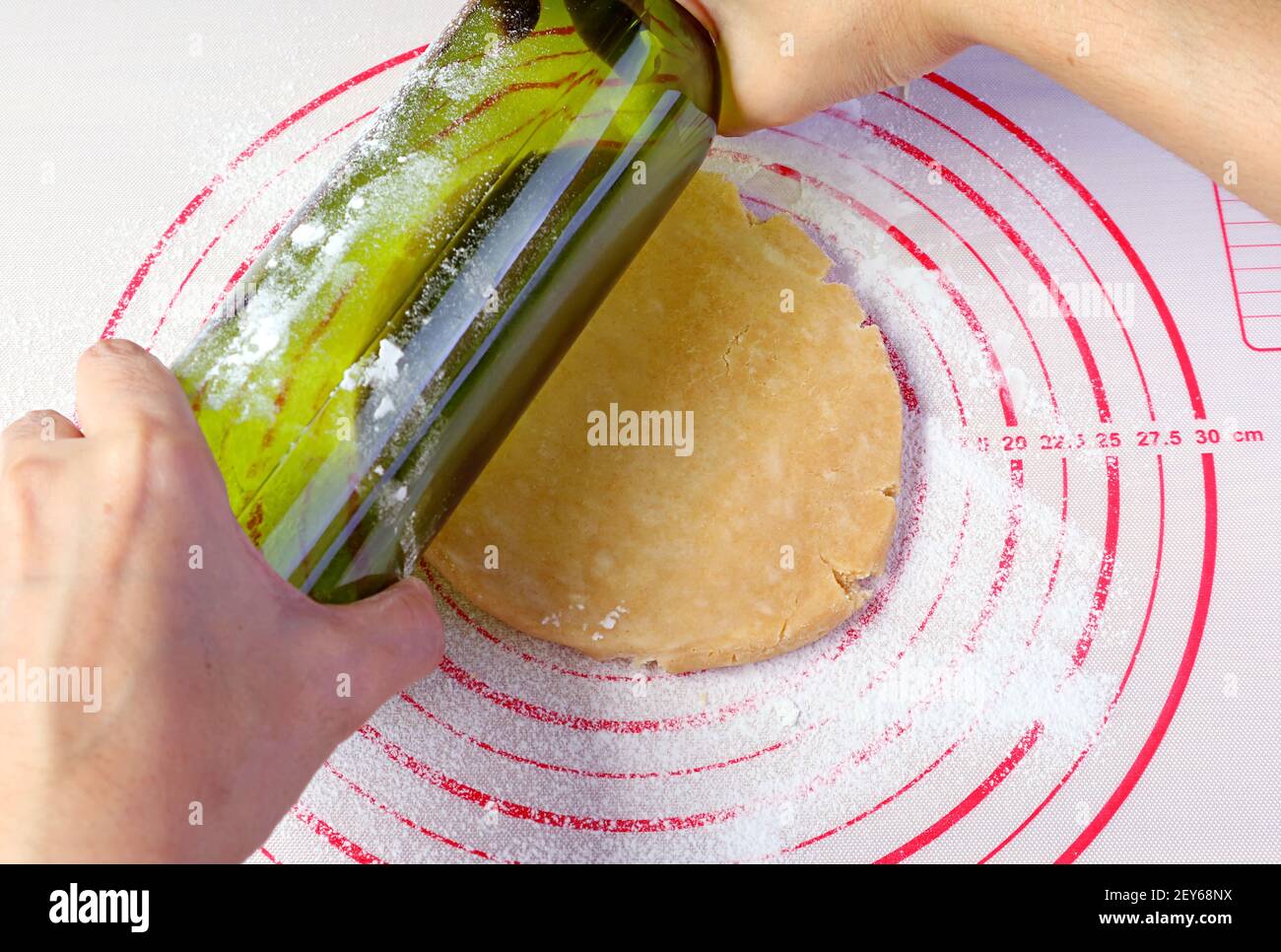 Pasta da torta arrotolabile a mano dell'uomo con una bottiglia di vino vuota per il concetto di cucina a casa Foto Stock