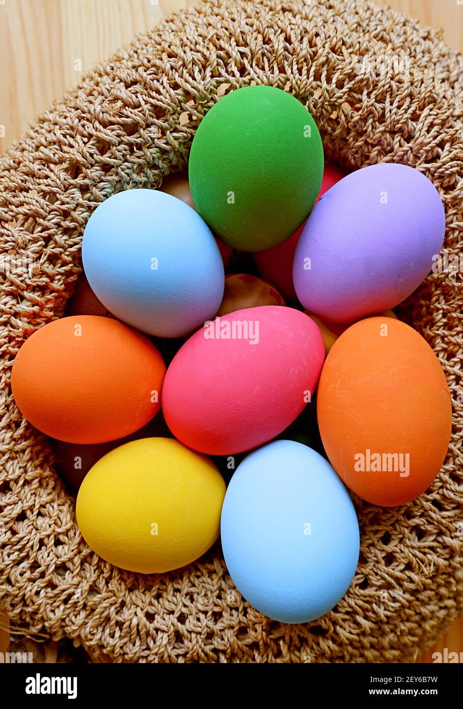 Immagine verticale di un cesto intessuto pieno di Pasqua colorata Uova Foto Stock