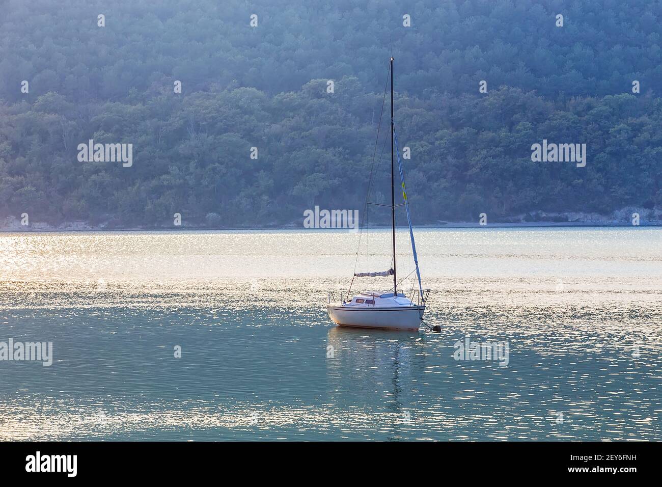 Barca a vela sul bellissimo lago tra montagne boscose Foto Stock