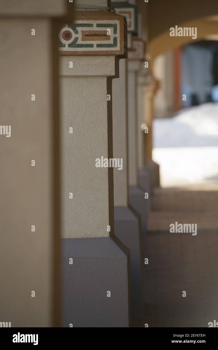 colonne ad arco progettate architettonicamente in inverno forme geometriche dipinte su colonne di cemento gialle o beige del sentiero sfondo verticale Foto Stock