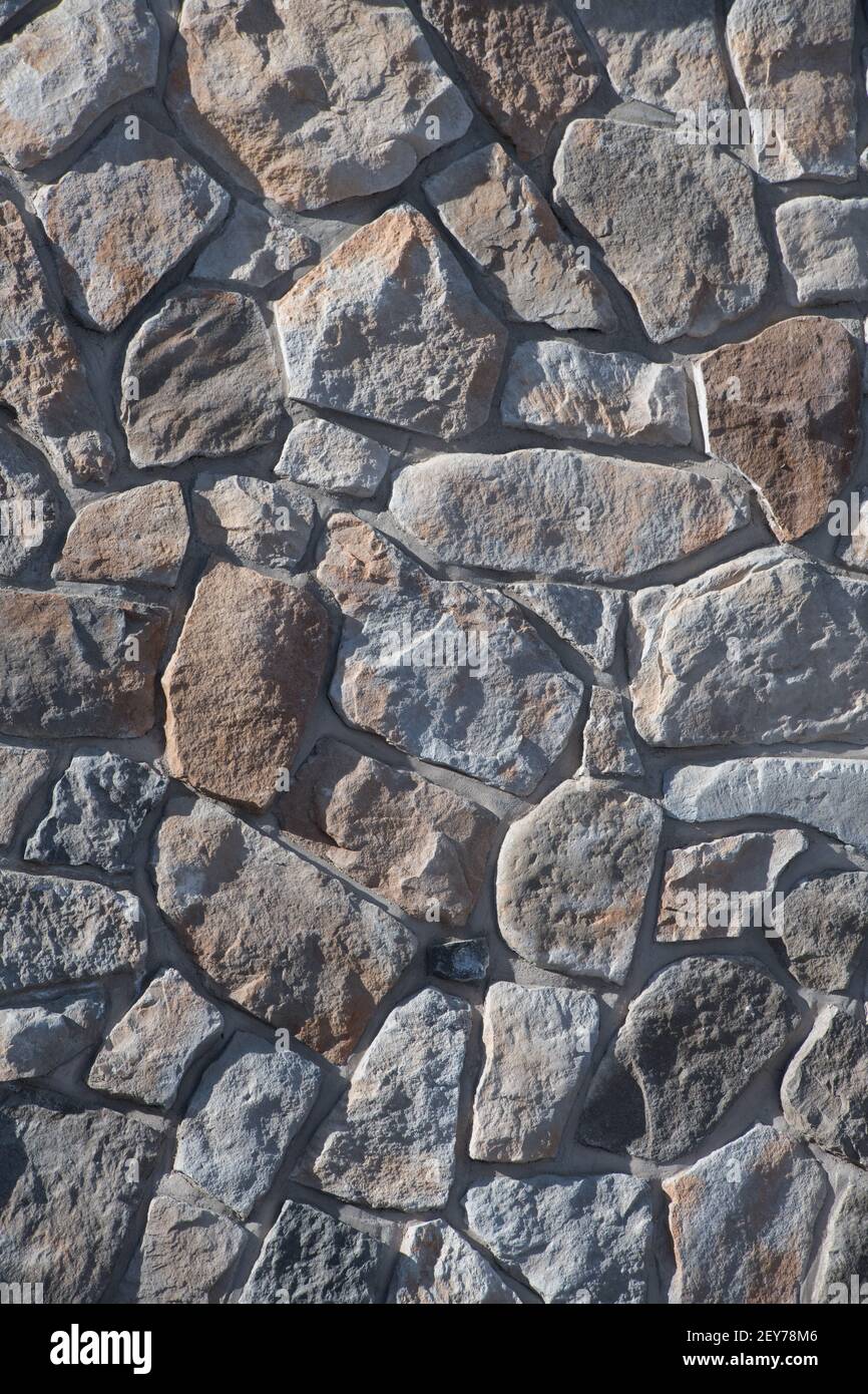 casualmente stranamente modellato pietre naturali o rocce esterno muro di pietra o muro di pietra muratura costruito mantenendo muro di casa esterno muratura sfondo verticale Foto Stock