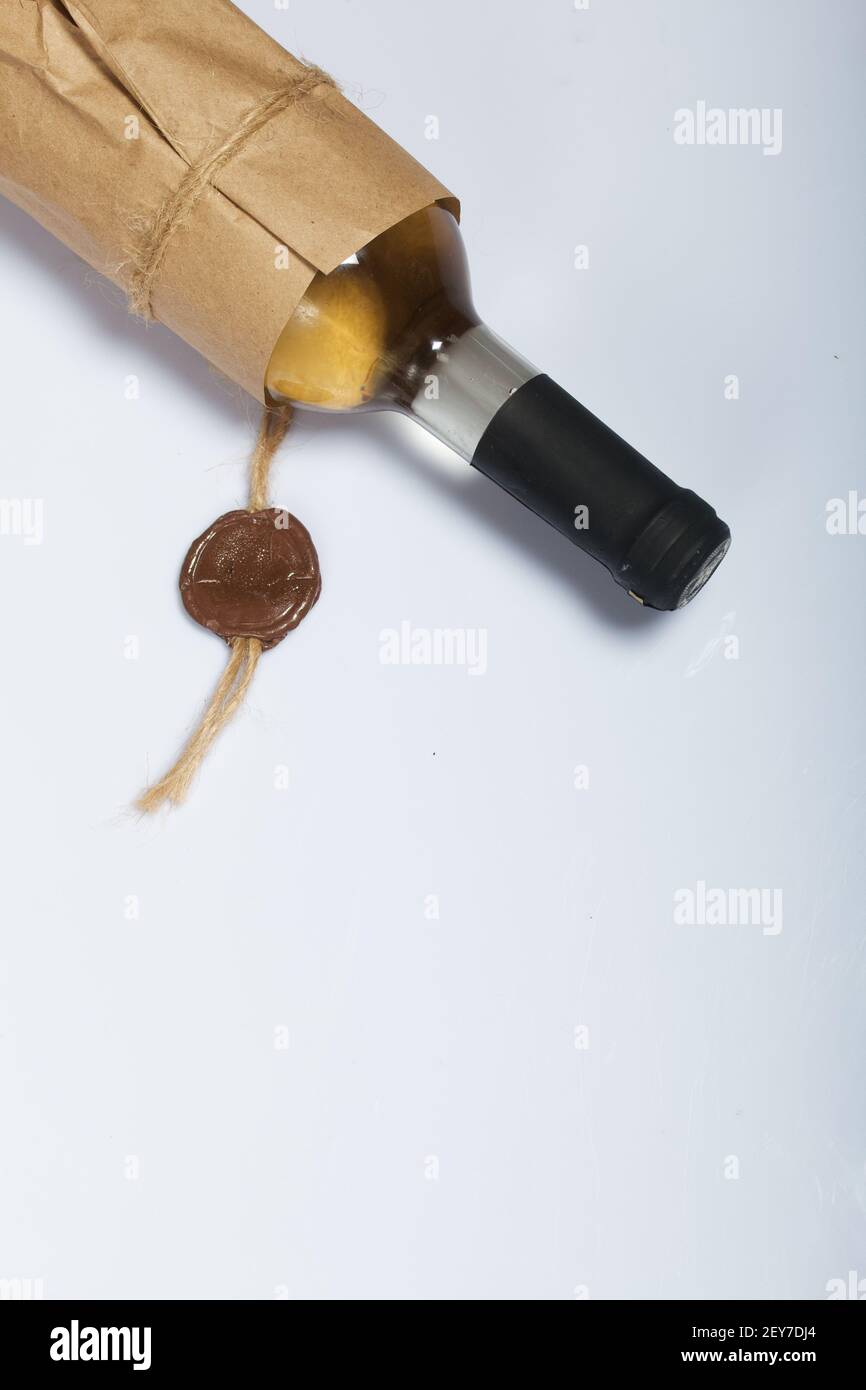 Bottiglia di alcool. Avvolto in carta. Su una superficie bianca. Foto Stock
