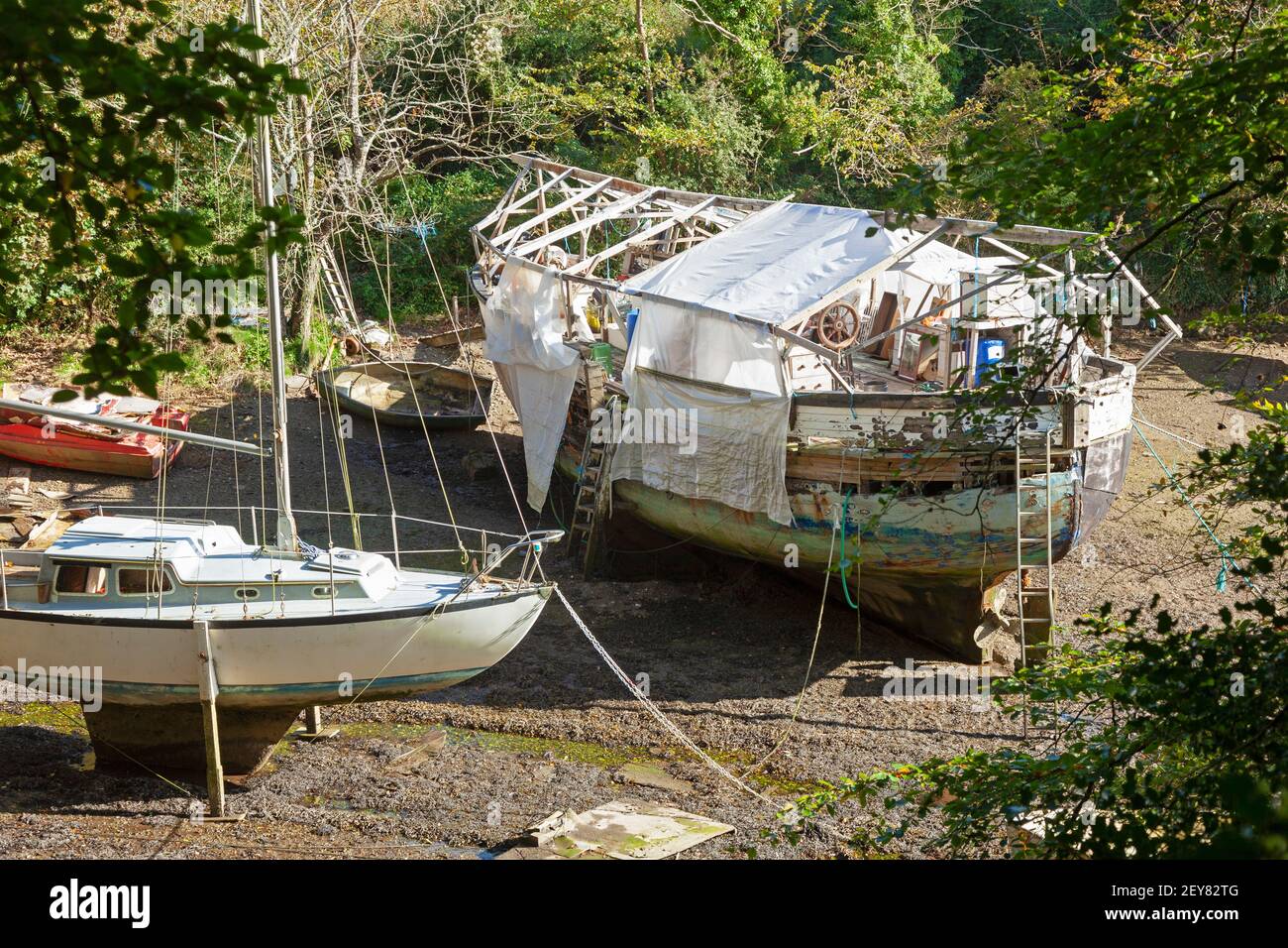 Barche in fase di ristrutturazione a bassa marea in un torrente riparato vicino a Falmouth e Penryn, Cornovaglia, Regno Unito Foto Stock