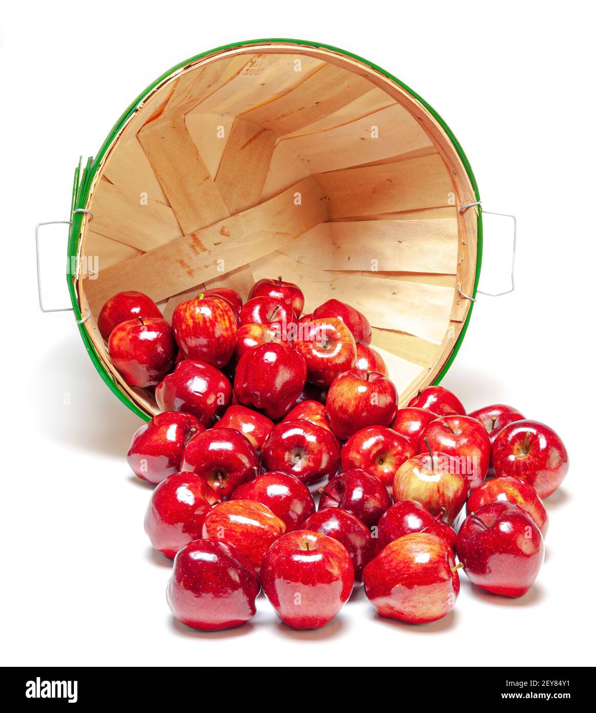 Colpo verticale di un cestino sul suo lato con le mele lucenti rosse che si sparano fuori. Isolato su bianco con ombre. Foto Stock