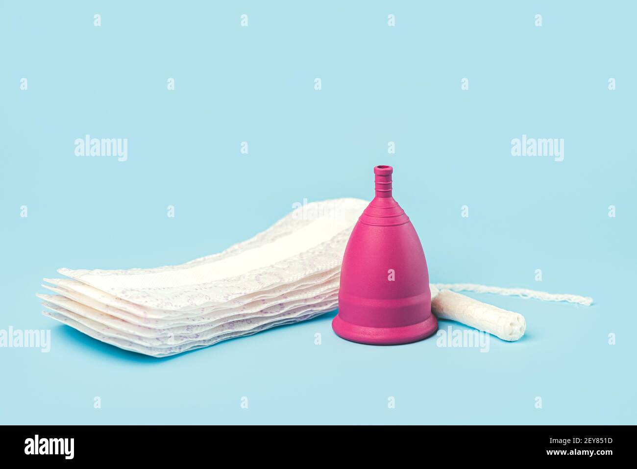 coppa mestruale in silicone con tampone e tamponi igienici mestruali o. tovaglioli su un fondo blu.femmina intimo alternativo igiene ginecologica conce Foto Stock