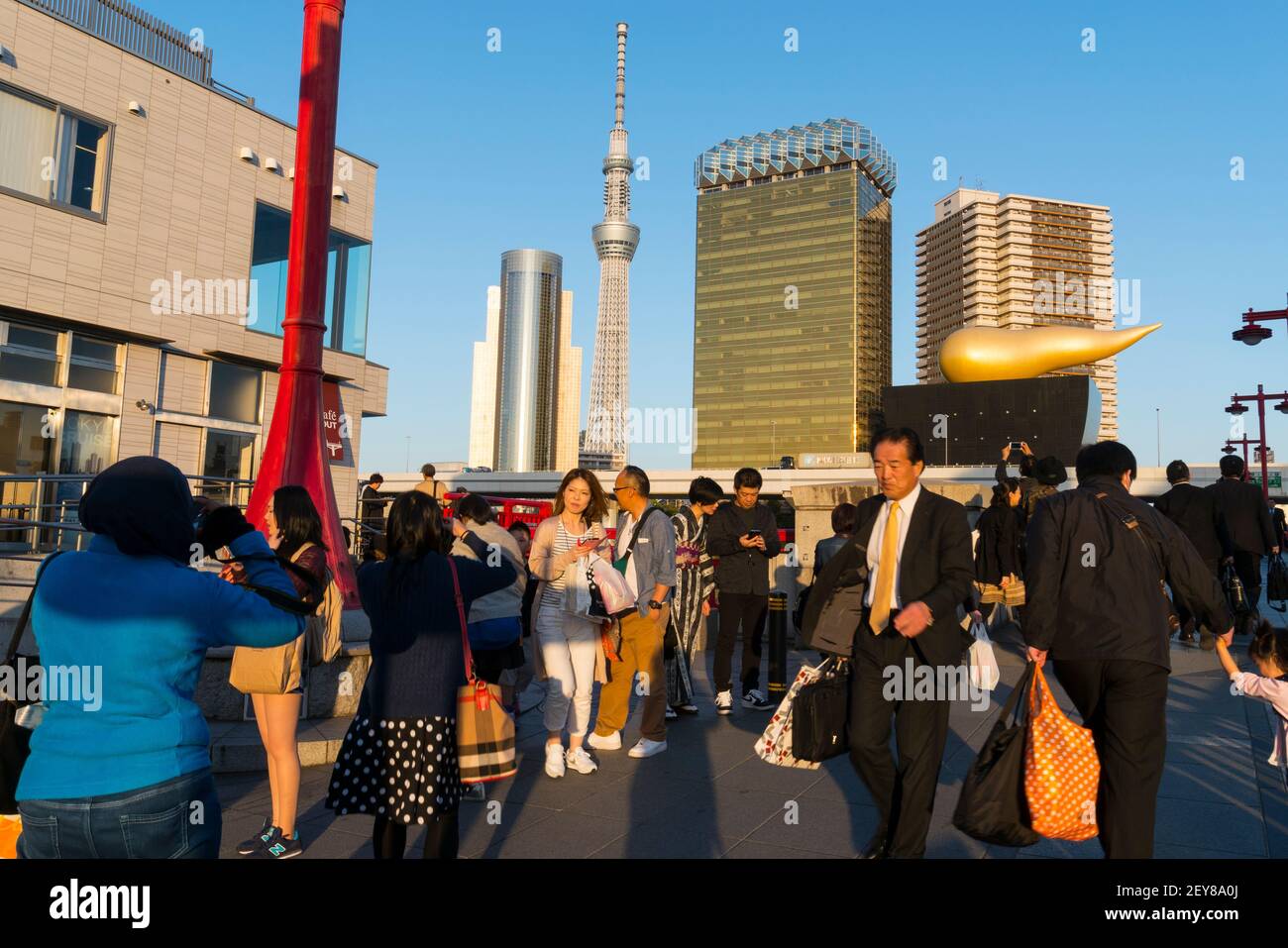 Persone al ponte Azumabshi in Asakusa Taito Ward Tokyo Giappone. Il tramonto illumina le persone e lo Sky Tree di Tokyo e il paesaggio urbano del centro. Foto Stock