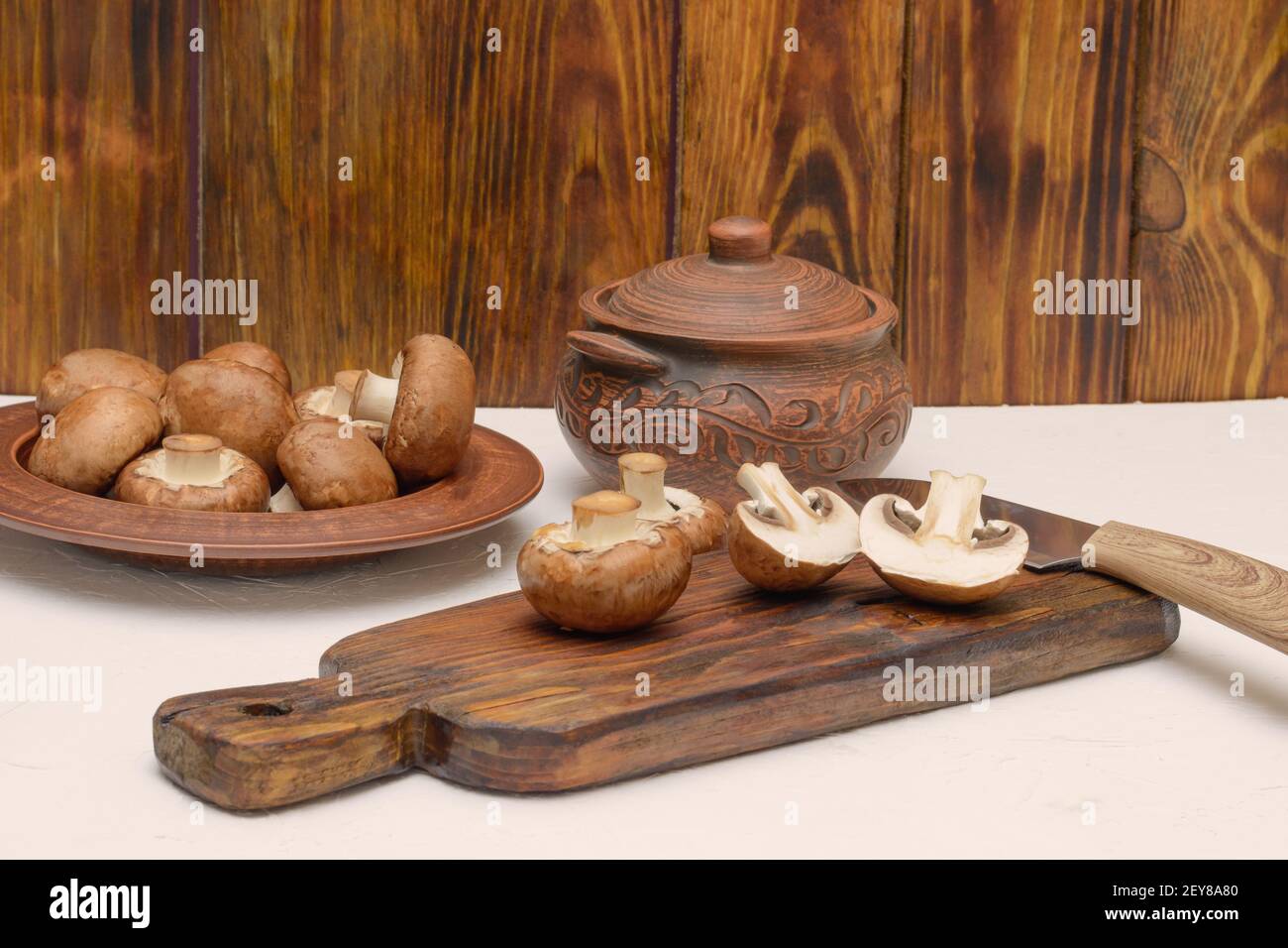 Processo di cottura dei funghi. Royal champignons marrone affettato ​​on tagliere di legno. Foto Stock