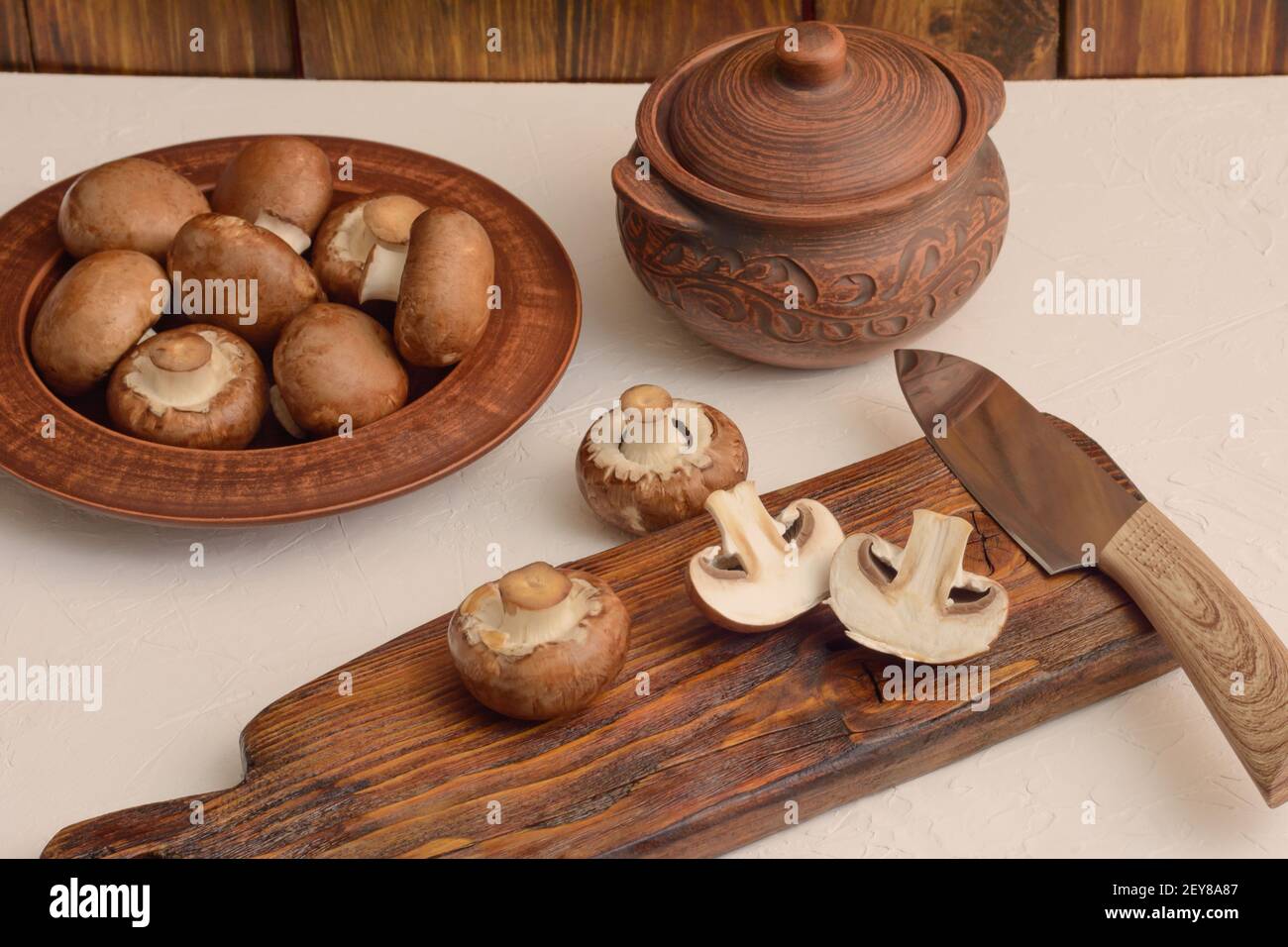 Champignon marroni per la cottura al forno. I funghi sono tritati sul taglio di tavola di legno. Foto Stock