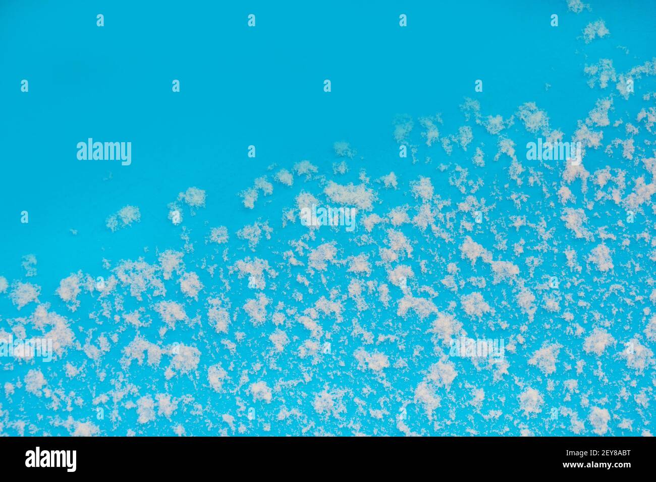 Sfondo invernale. Fiocchi bianchi di neve su tessuto blu. Copiare lo spazio e posizionare il testo. Sfondo sfocato, vista nebbia. Foto Stock