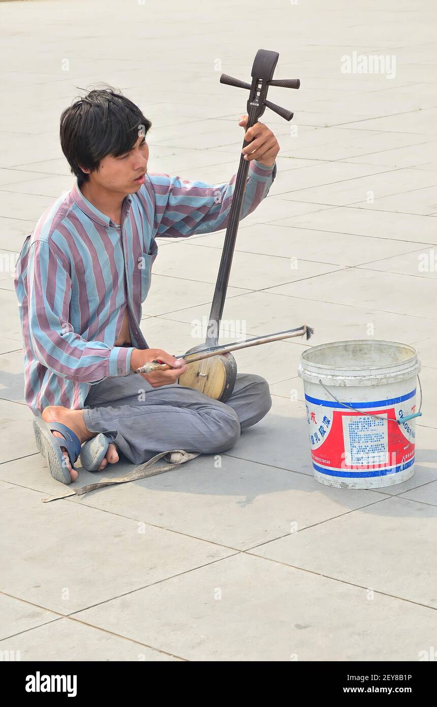 Pechino, Cina-Maggio 26,2013: Un mendicante che suona l'erhu, strumento tradizionale cinese, per strada. Punti di messa a fuoco selettivi Foto Stock