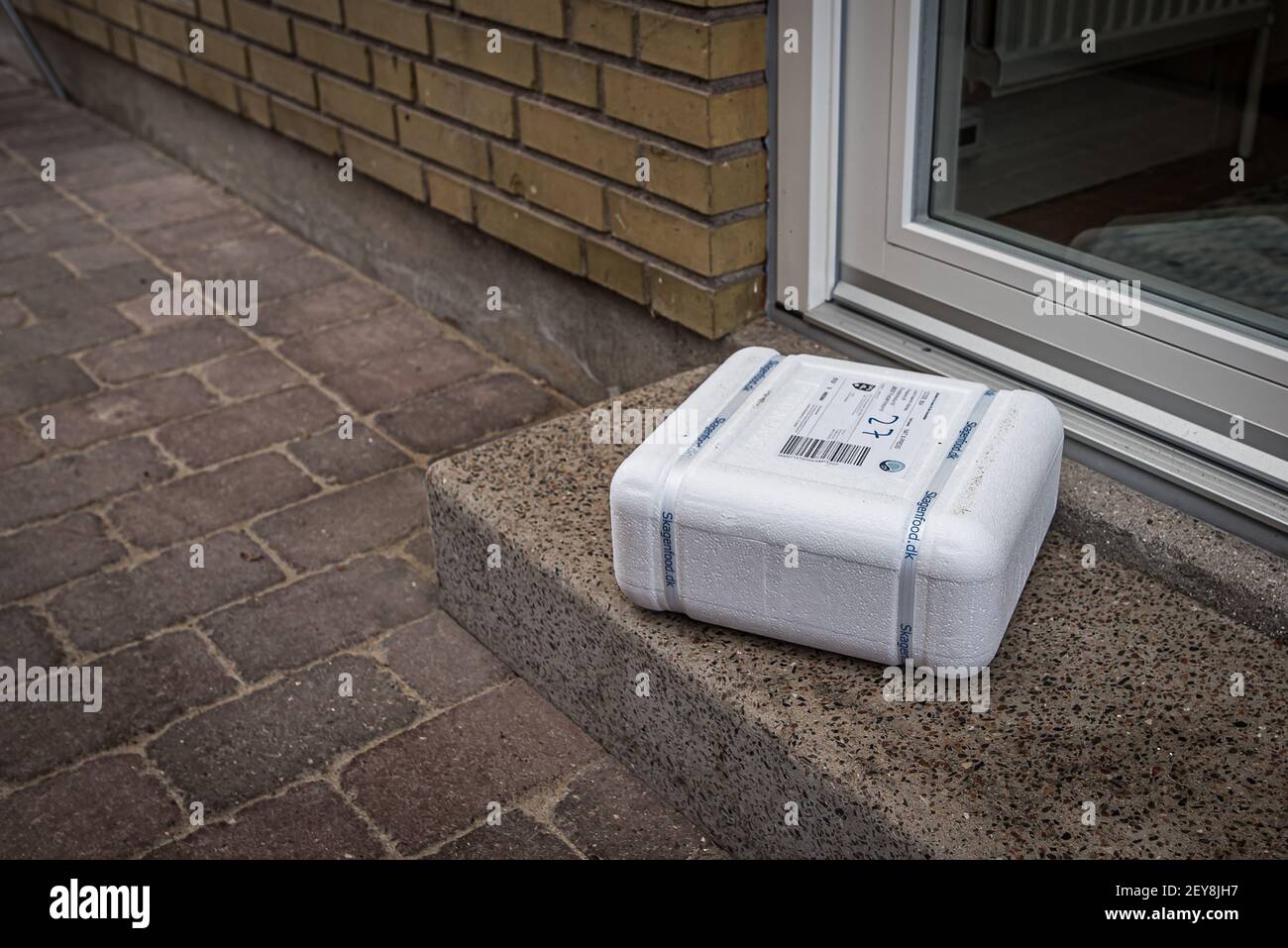 Un pacchetto in polistirolo bianco sulla porta d'ingresso, all'esterno della porta d'ingresso, Danimarca, Mars 4, 2021 Foto Stock