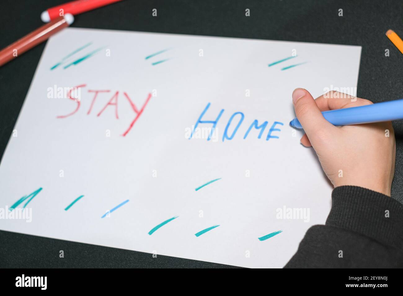 Bambino scuola ragazzo disegno soggiorno slogan casa su un foglio in covid19 pandemia malattia, cura dei bambini Foto Stock