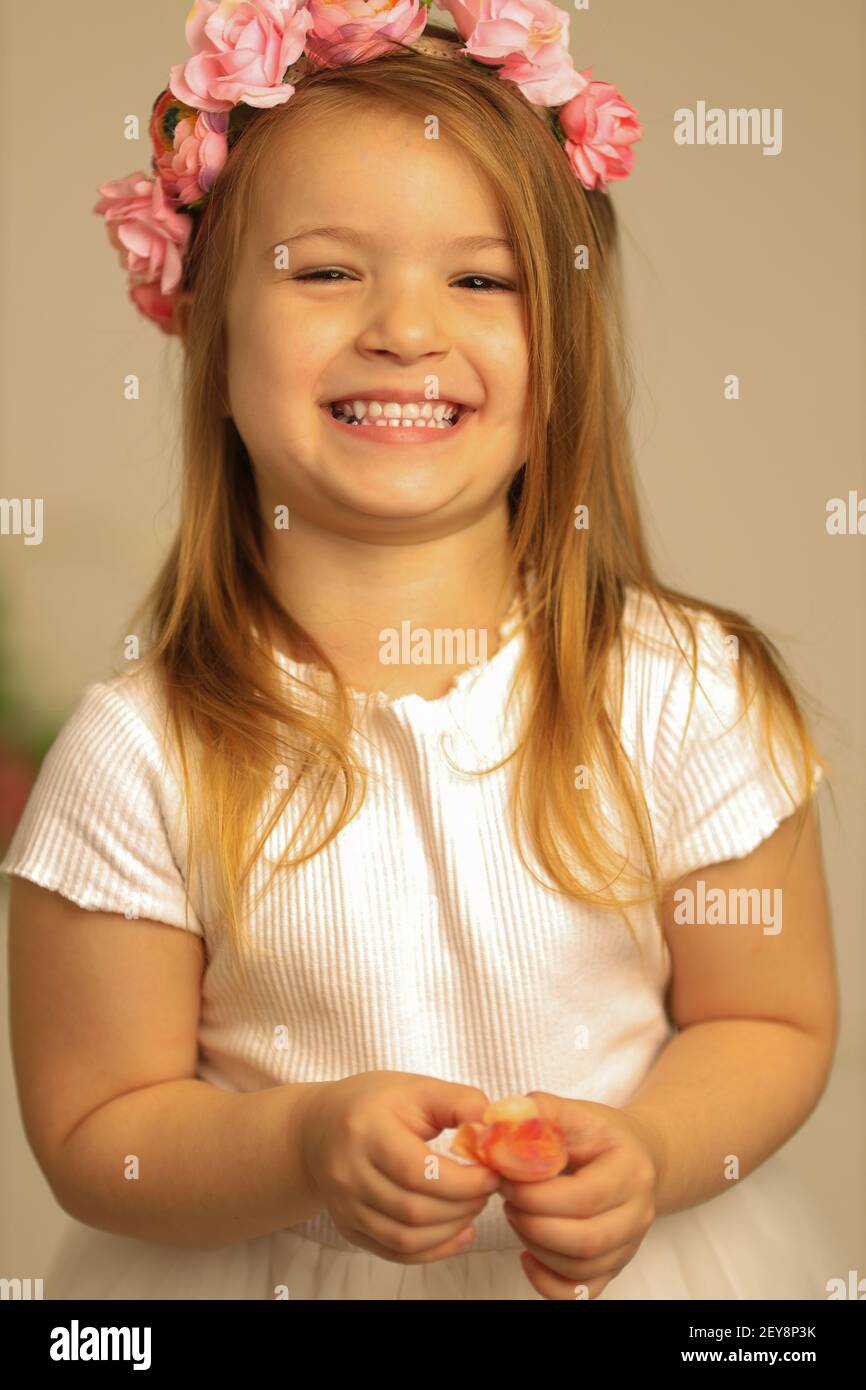 Ritratto di una ragazza angelica rossa che indossa una corona di fiori su uno sfondo crema. Stagione primavera-estate Foto Stock