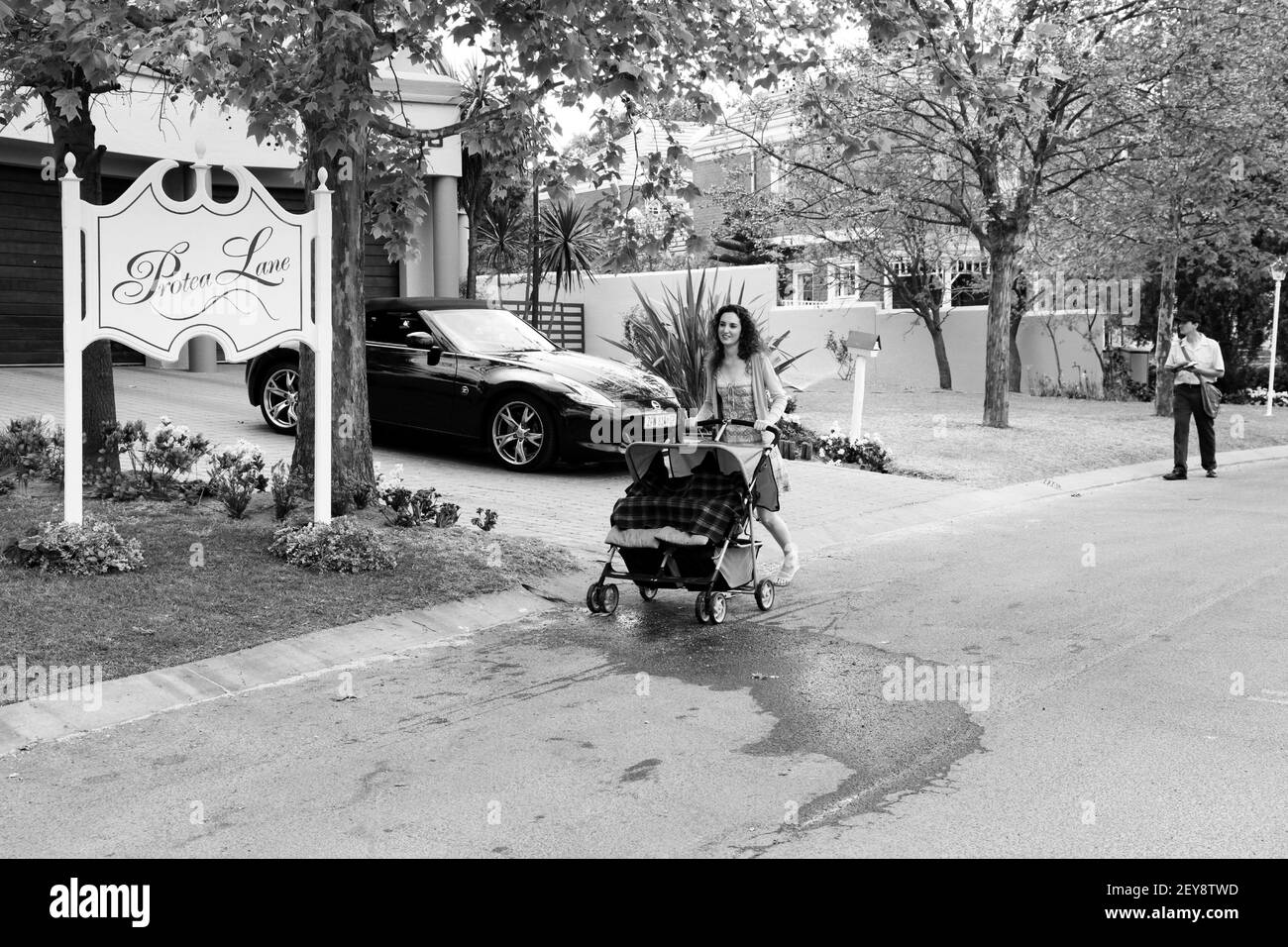 JOHANNESBURG, SUDAFRICA - 05 gennaio 2021: Johannesburg, Sudafrica - 11 settembre 2010: Mamma con pram e Mailman che consegnano la posta in un sub ricco Foto Stock