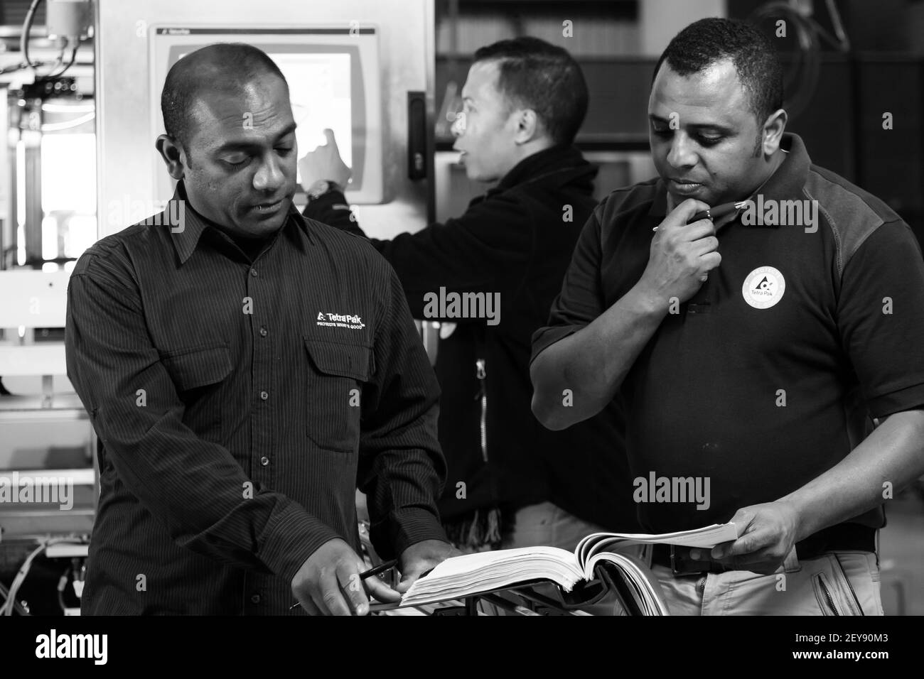 JOHANNESBURG, SUD AFRICA - 06 gennaio 2021: Johannesburg, Sud Africa - 13 agosto 2015: Diversi lavoratori maschili che controllano un libro di istruzioni su un pacchetto Foto Stock