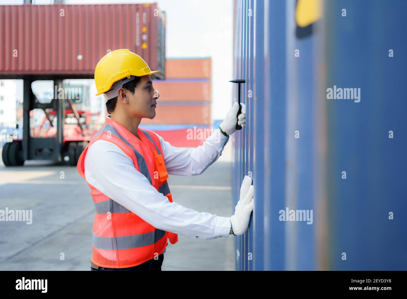 Operatore asiatico che utilizza l'attrezzo Chipping Hammer per controllare il contenitore dopo il completamento della riparazione per preparare la consegna al cliente. Foto Stock