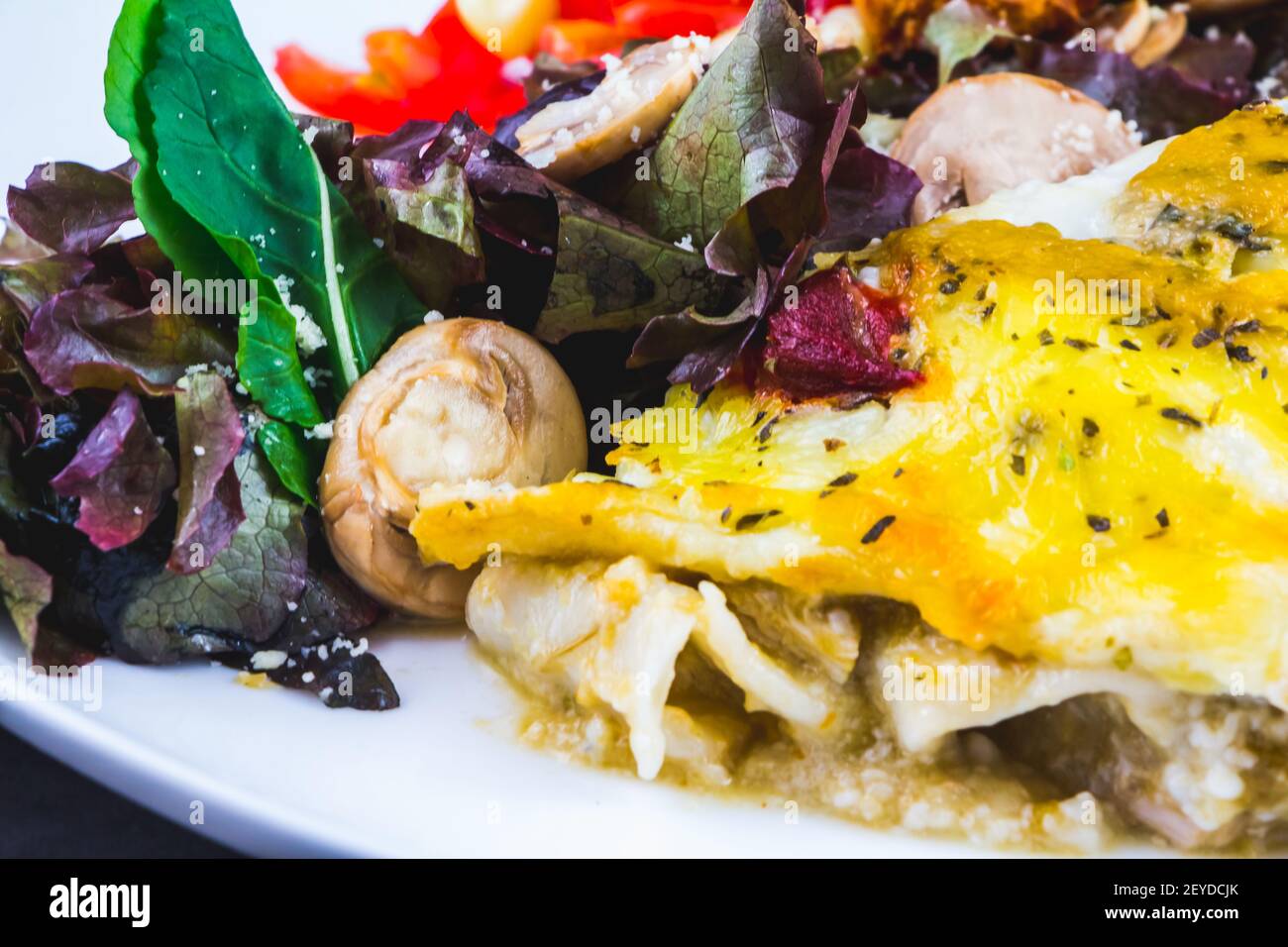 Porzione di lasagna farcita con insalata verde Foto Stock