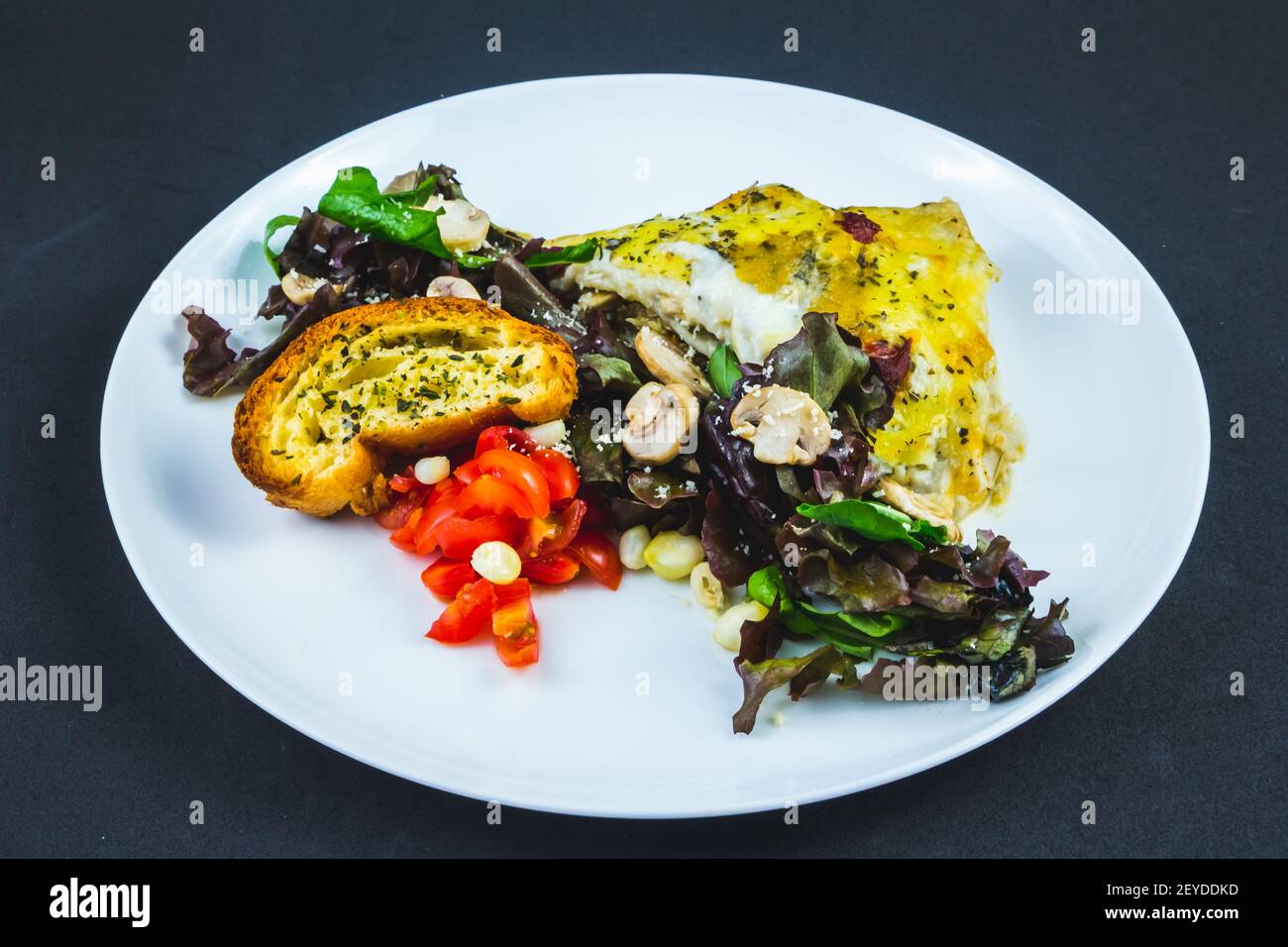Porzione di lasagna farcita con insalata verde Foto Stock
