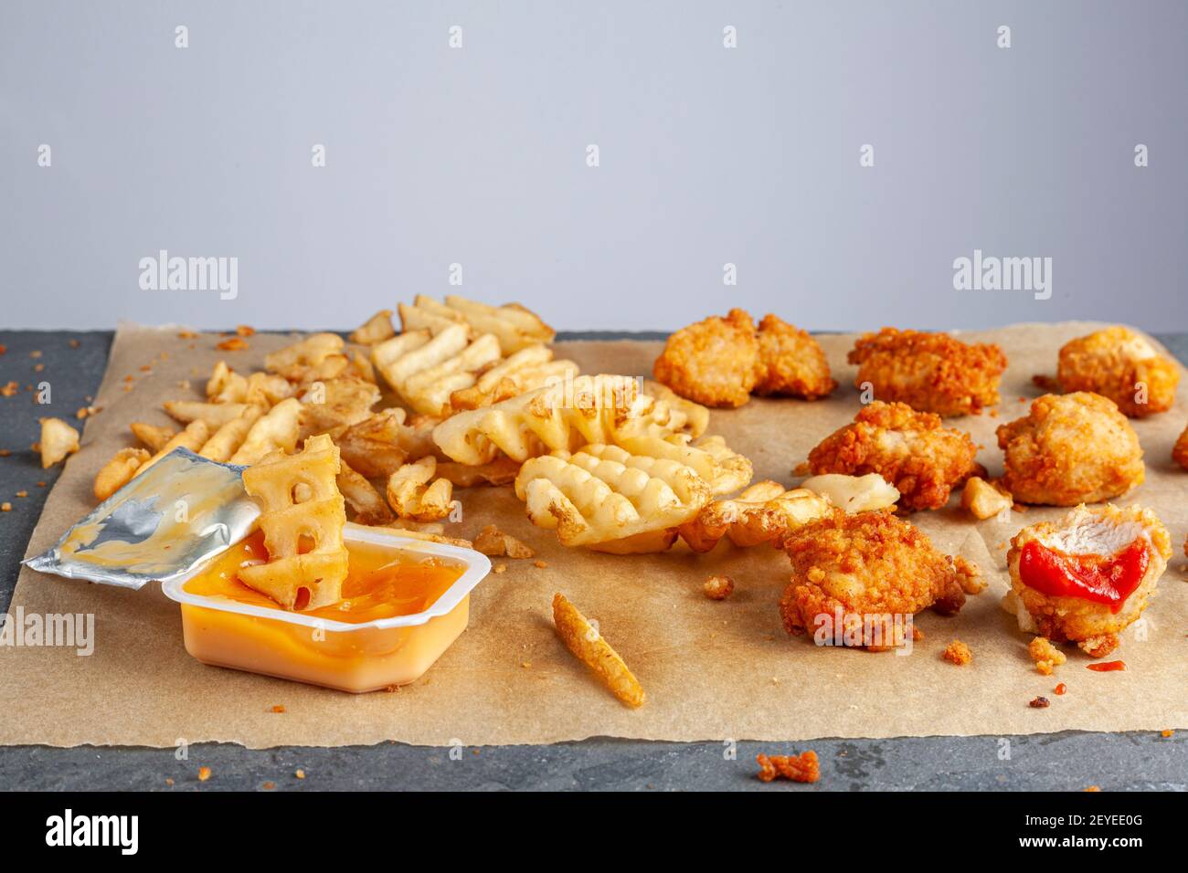 Rapida e pratica immagine rapida degli alimenti con messa a fuoco selettiva da vicino di pepite di pollo fritte e fritte immerse in salse sulla carta da forno. RUF Foto Stock