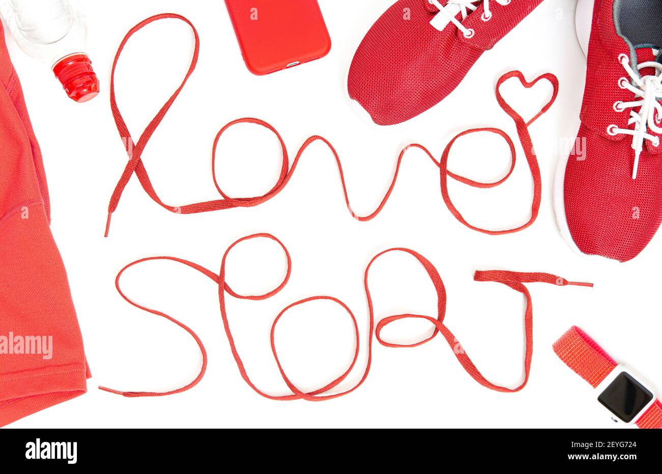 La disposizione piatta degli accessori da running include una scritta LOVE SPORT fatta di scarpe atletiche, scarpe, smartphone, smartwatch, top e una bottiglia d'acqua iso Foto Stock