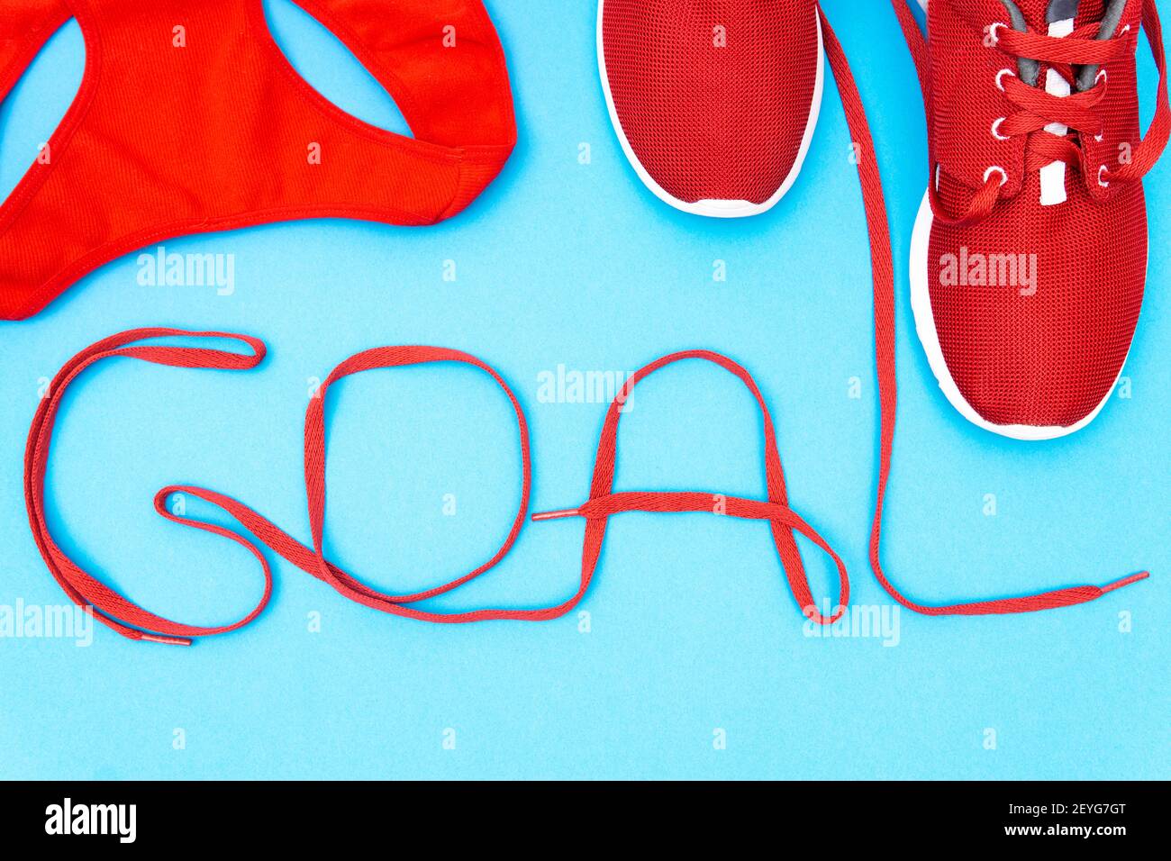 Sneakers atletiche rosse e una canotta da training con SCRITTA GOL fatta di scarpe su sfondo blu. Creativo piatto Lay, attivo stile di vita motivazione c Foto Stock