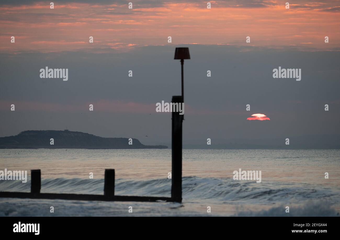 Il sole sorge sulla spiaggia di Boscombe a Dorset. Data immagine: Sabato 6 marzo 2021. Foto Stock