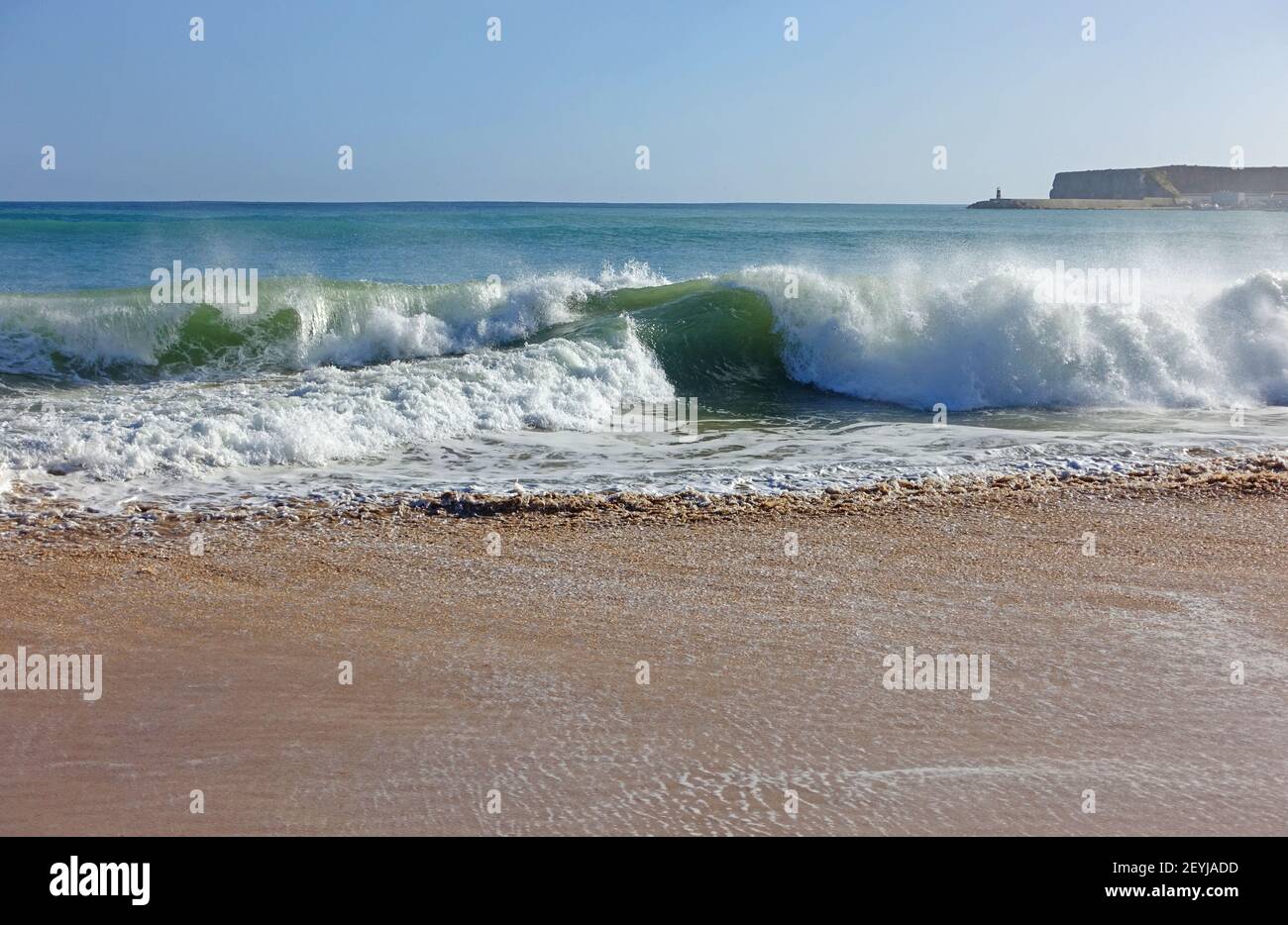 Onde che si infrangono su una spiaggia di sabbia nell'algarve Foto Stock