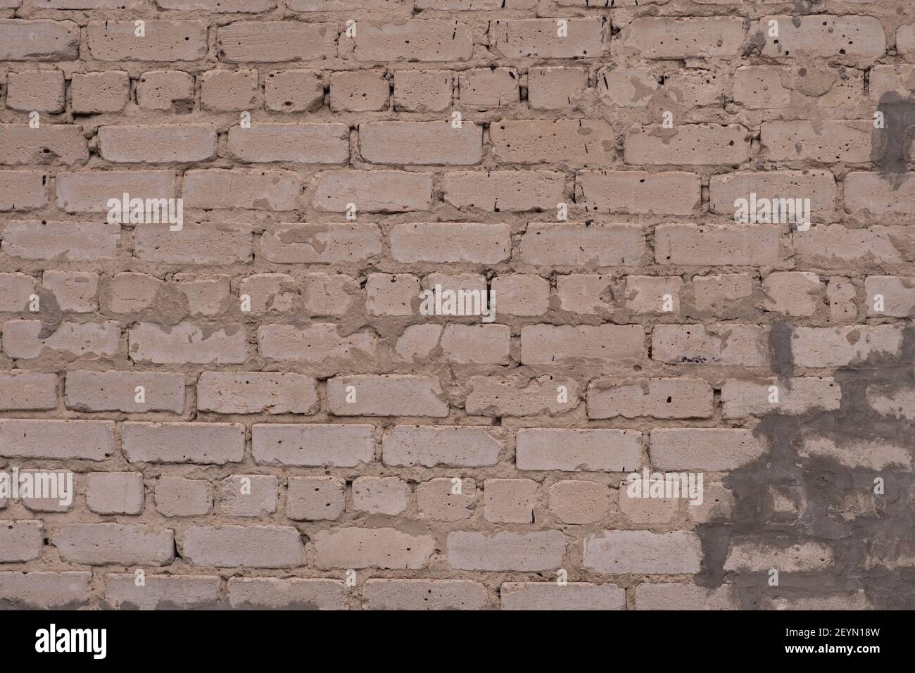 Il muro di mattone beige è grosso modo fatto. Foto Stock