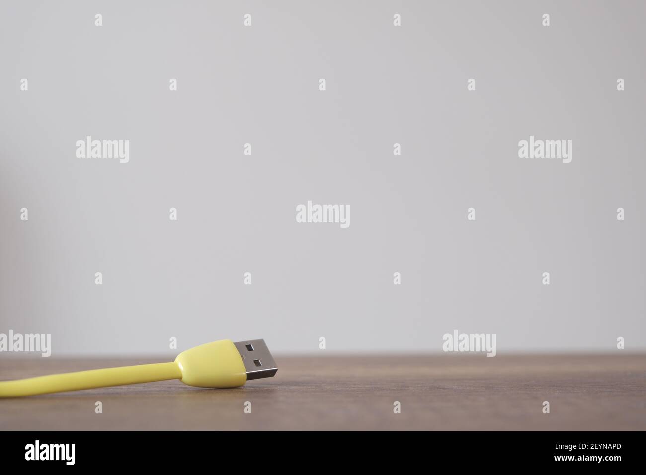 Cavo di tipo USB di colore giallo che si trova su un tavolo di legno scuro con fondo parete isolato. Foto Stock