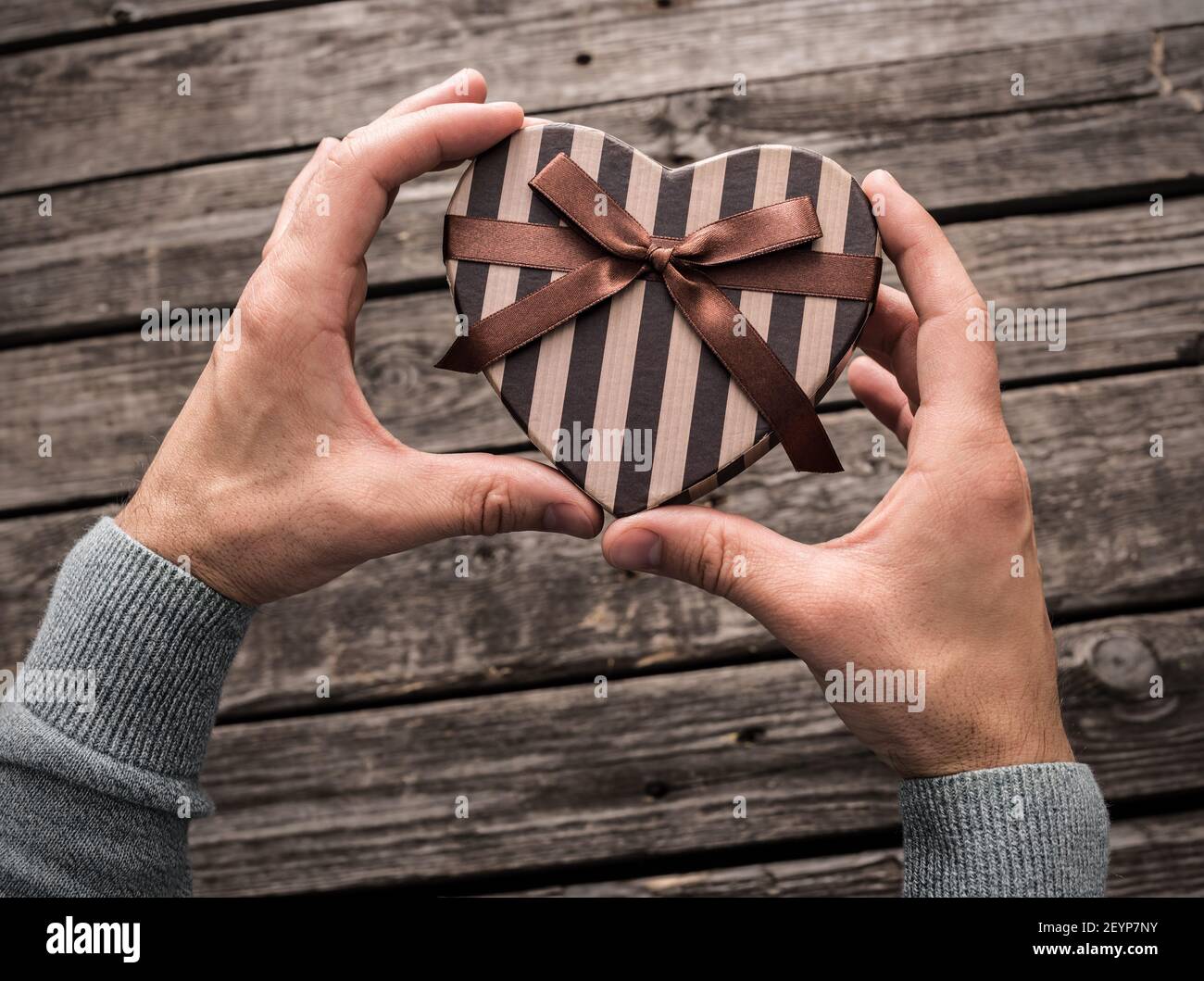 Confezione regalo a forma di cuore nelle mani dell'uomo 39. Foto Stock