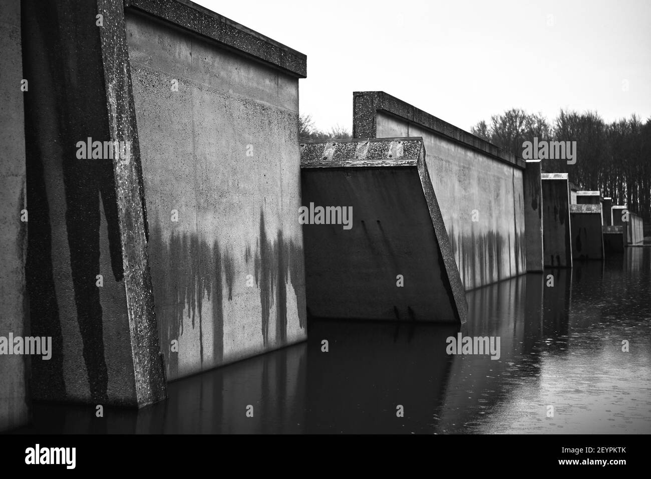 Un'immagine in bianco e nero di un canale con un vecchio muro distrutto Foto Stock