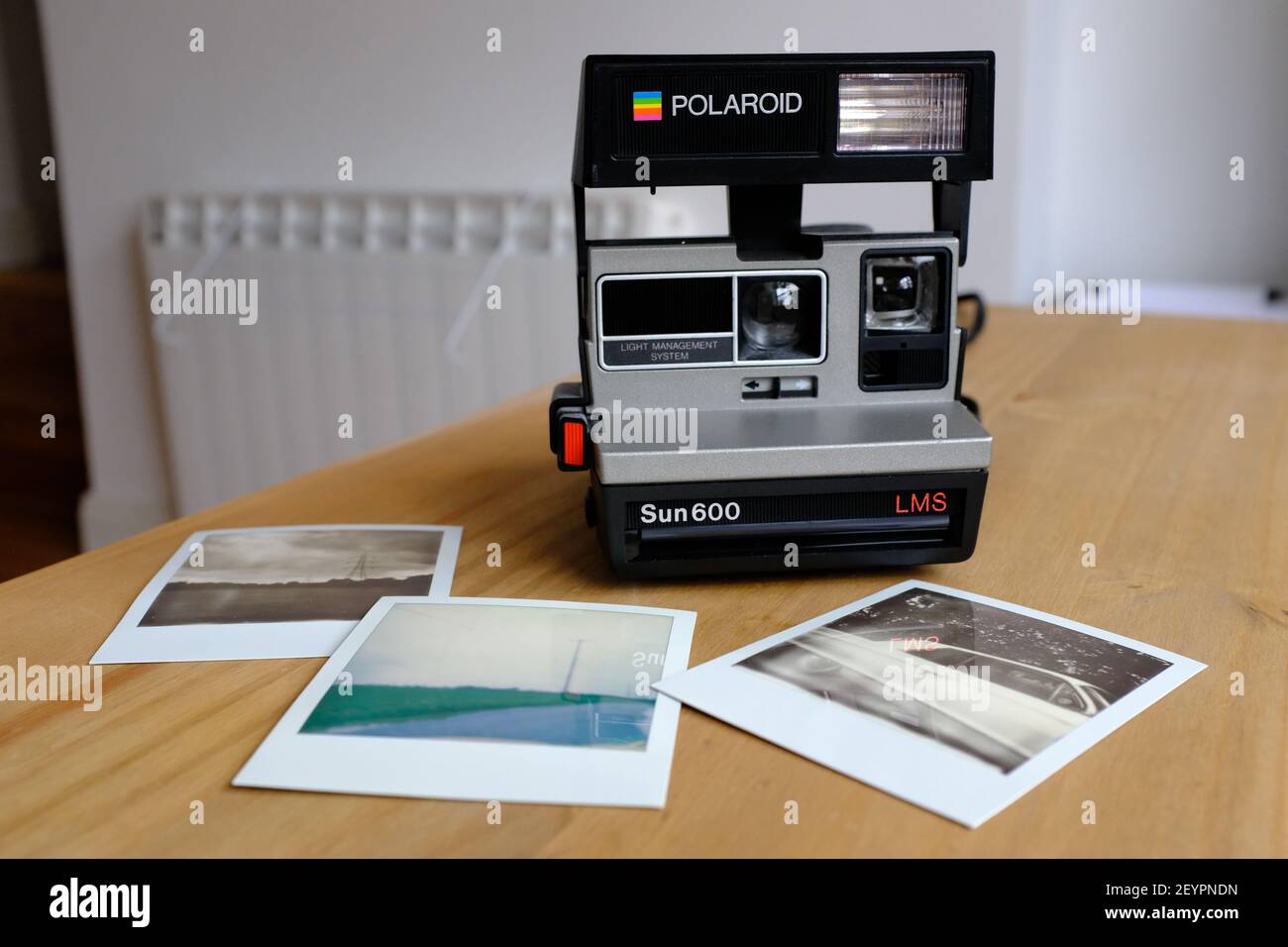 LONDRA - 6 MARZO 2021: Una macchina fotografica istantanea con una selezione di stampe su un piano di lavoro in legno. Foto Stock