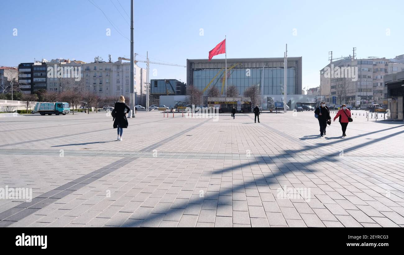 istanbul, una delle piazze più note di piazza taksim durante il giorno di sole, turisti che camminano nella piazza con maschera medica e grande bandiera turca. Foto Stock