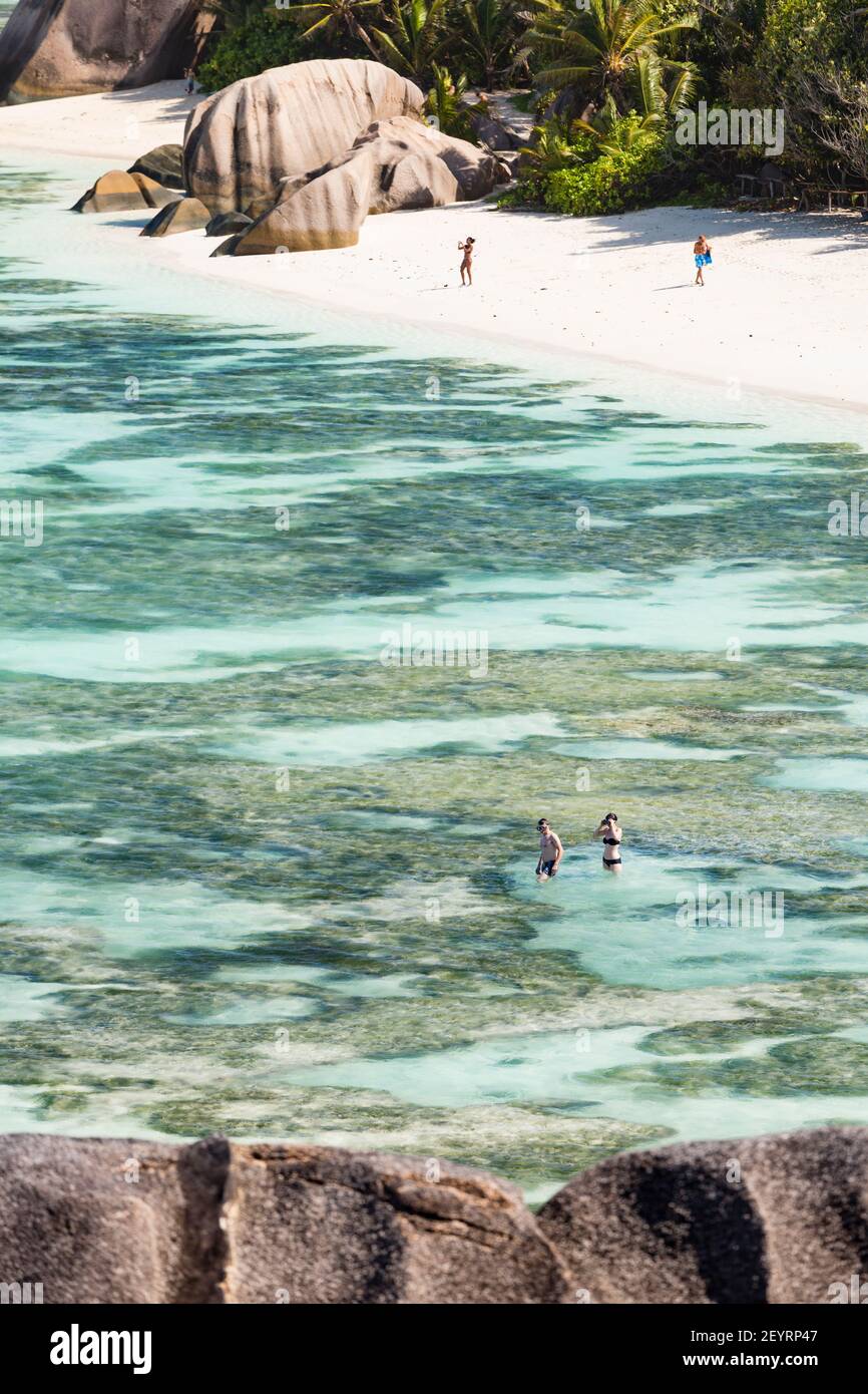 Alcuni dei primi turisti sulla spiaggia e snorkeling nella laguna di Anse Source d'Argent in La Digue, Seicelle Foto Stock