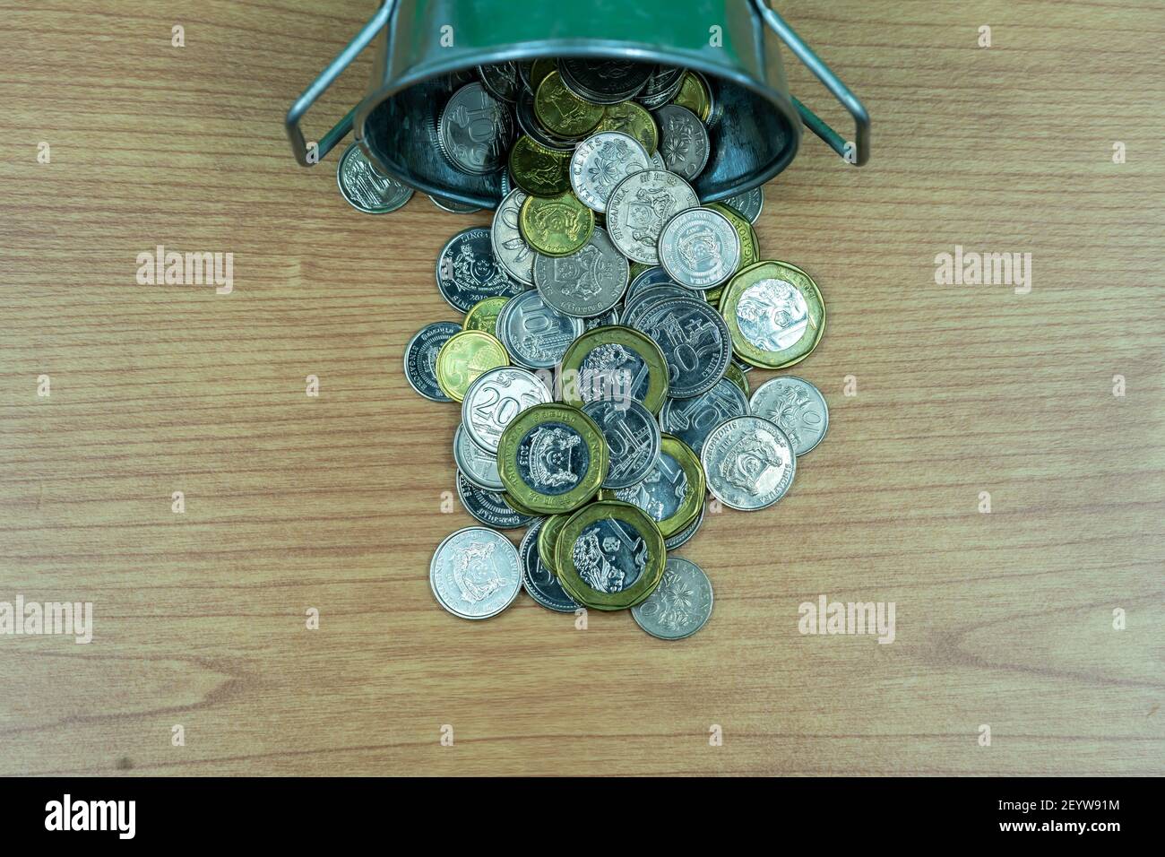 Pieno di monete di denaro in un secchio di stagno su sfondo blu per investimento, business, finanza e risparmio concetto di denaro Foto Stock