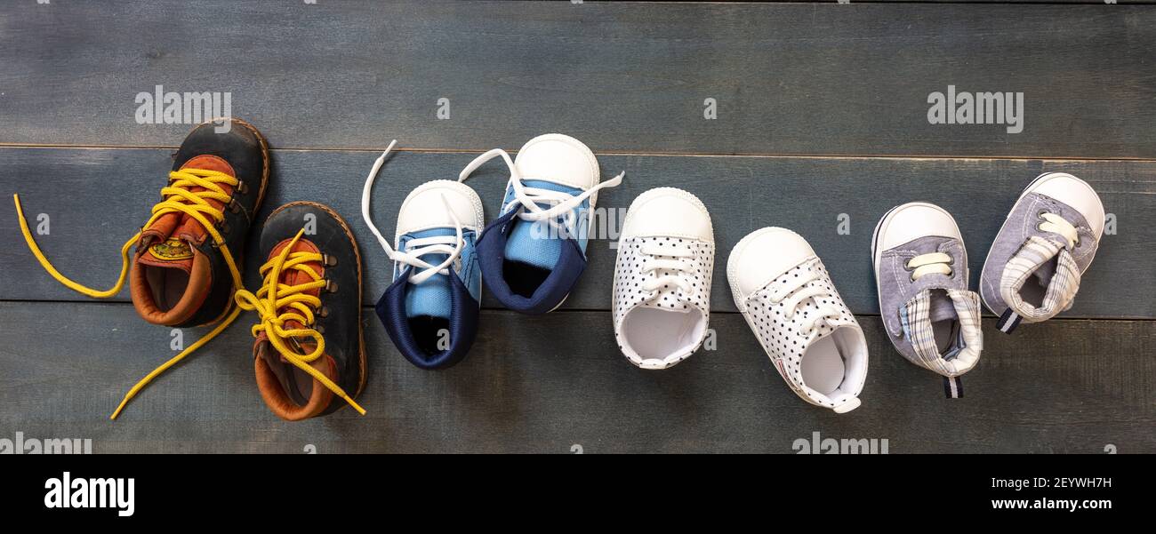 I primi passi del bambino. Quattro paia di scarpe da ragazzo varietà su  sfondo in legno di colore blu, vista dall'alto. Scarpe da bambino,  stivaletti e scarpe morbide per neonati in fila