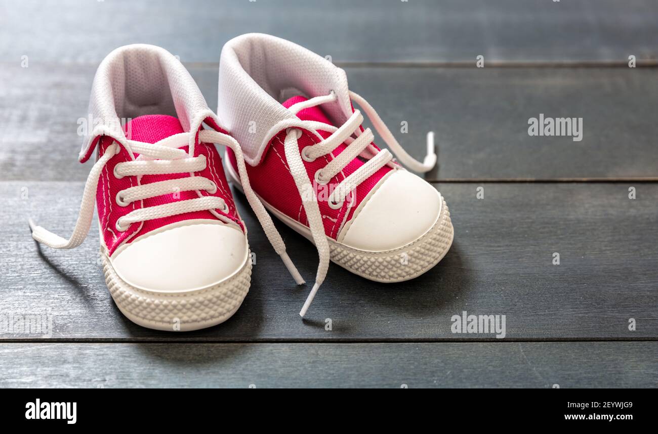 Scarpe sportive baby girl su pavimento in legno di colore blu. Scarpe da  ginnastica rosa per bambini di piccole dimensioni, vista in primo piano con  stivaletti in tela. Spazio, modello invito scheda