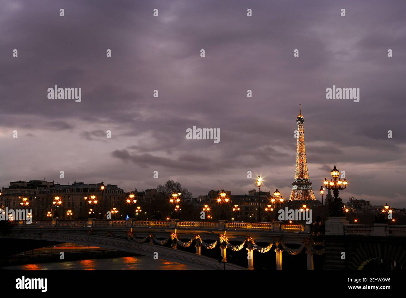 La Torre Eiffel si illumina dietro il ponte sulla Senna al tramonto a Parigi, Francia. Foto Stock