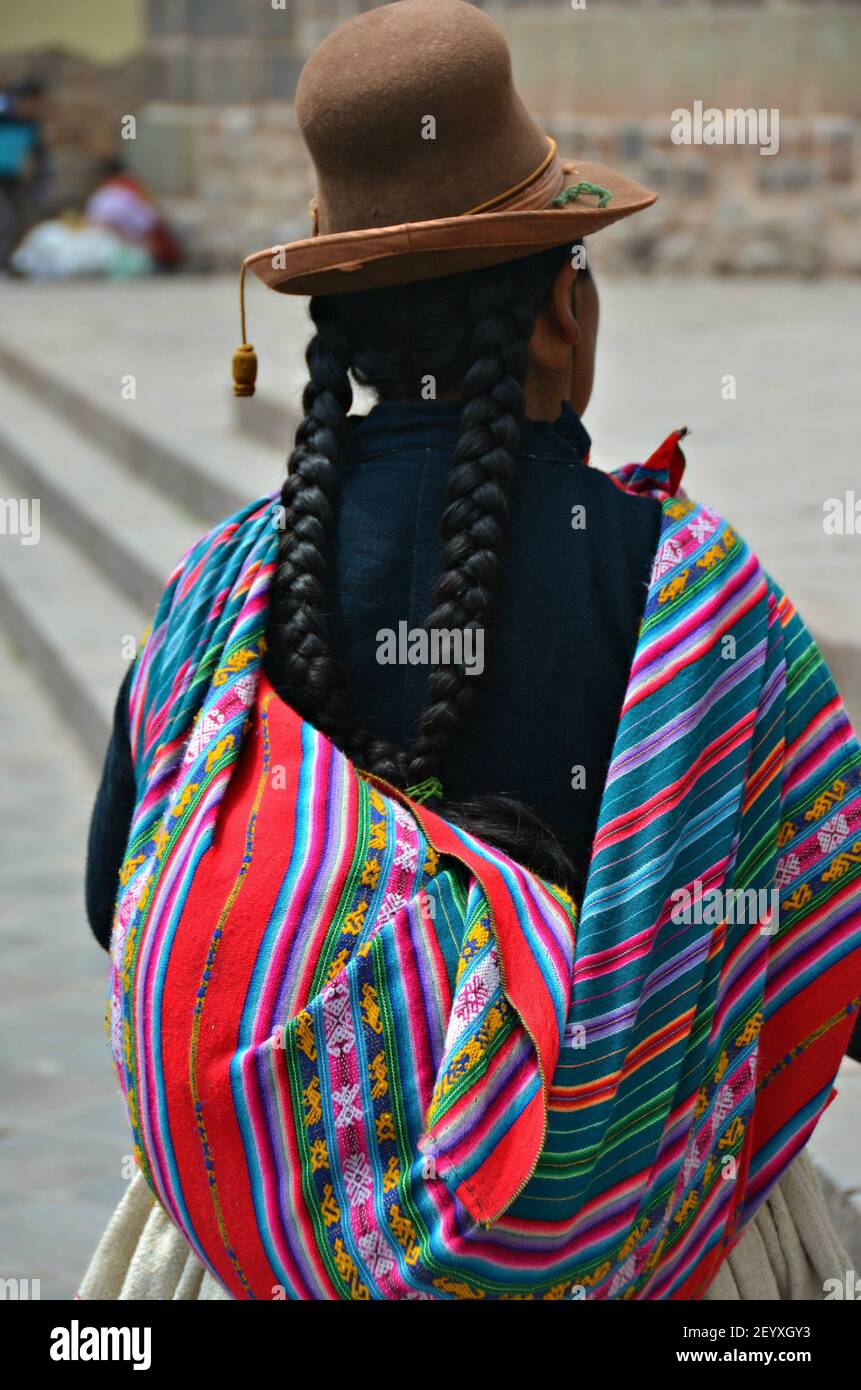 Donna indigena con lunghe trecce di capelli neri, abiti tradizionali  colorati e un cappello marrone di ciotolo feltro per le strade di Cusco  Perù Foto stock - Alamy
