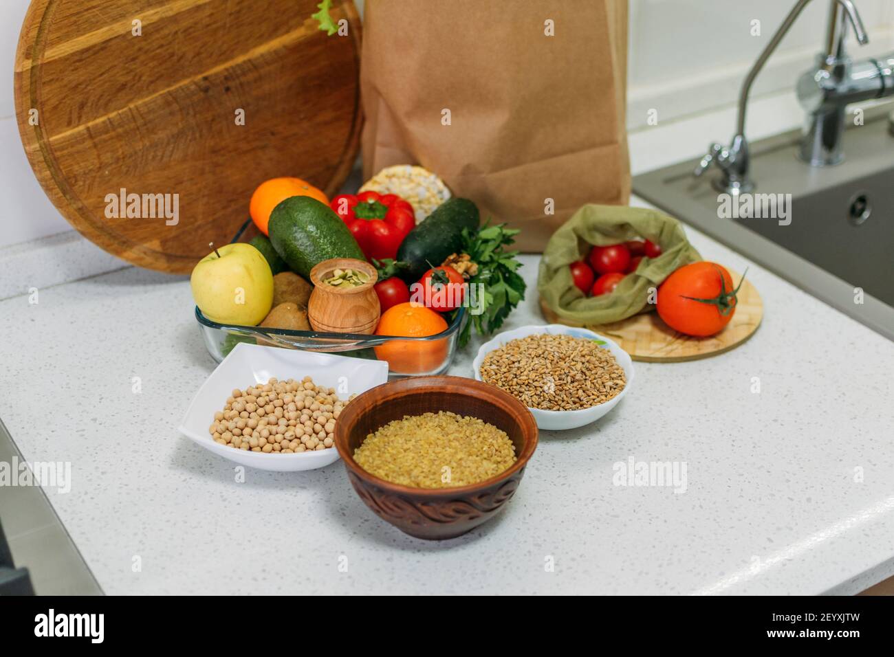Giornata mondiale di Vegan. Diverse verdure crude, erbe e cereali sul tavolo da cucina. . Cibo fresco crudo verdure di stagione in cucina casalinga. Vegetariano Foto Stock