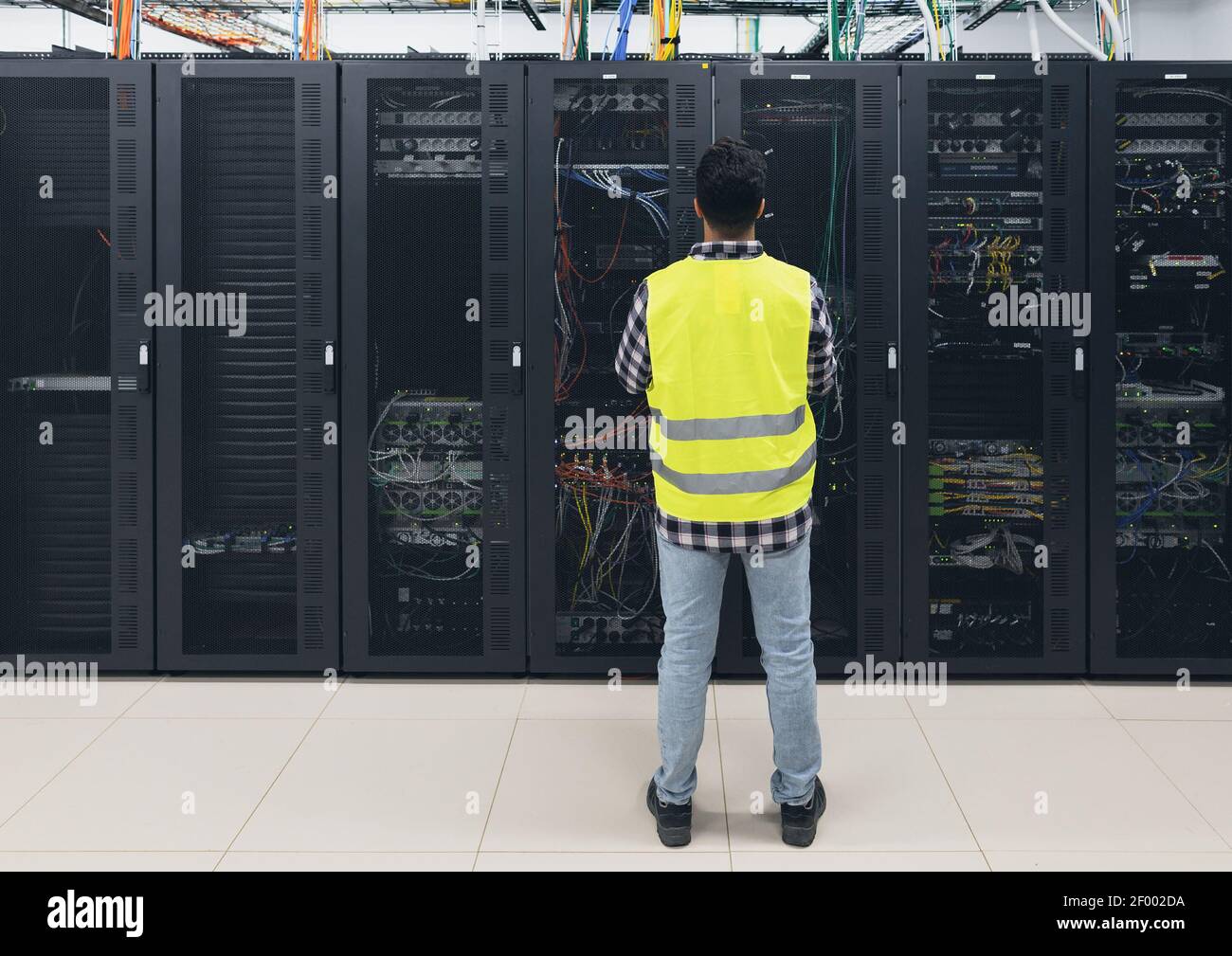 Ingegnere informatico maschile che lavora all'interno del database della sala server Foto Stock