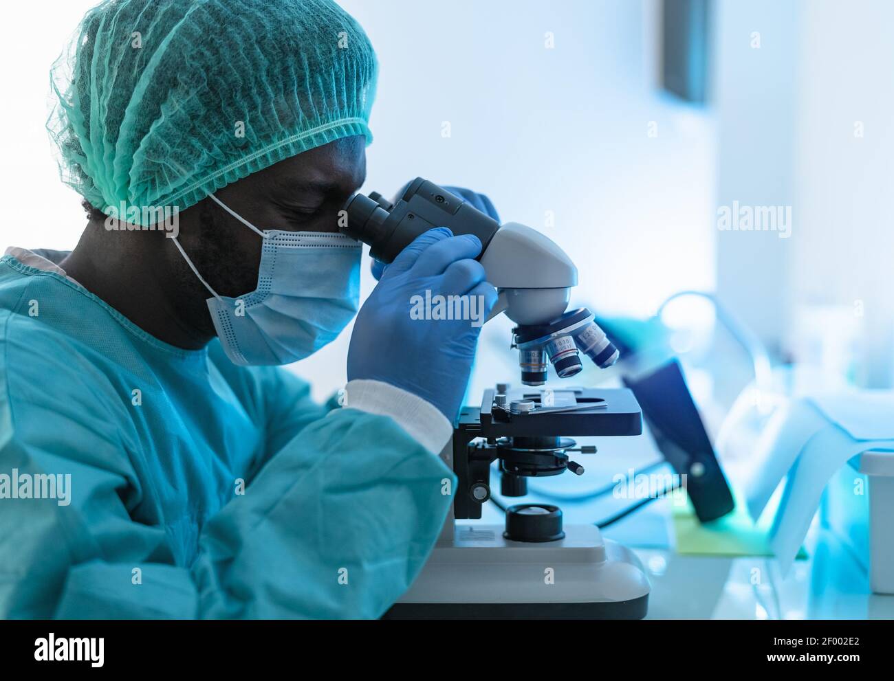 Scienziato che lavora in laboratorio esaminando il coronavirus attraverso il microscopio - Scienza e concetto di tecnologia Foto Stock
